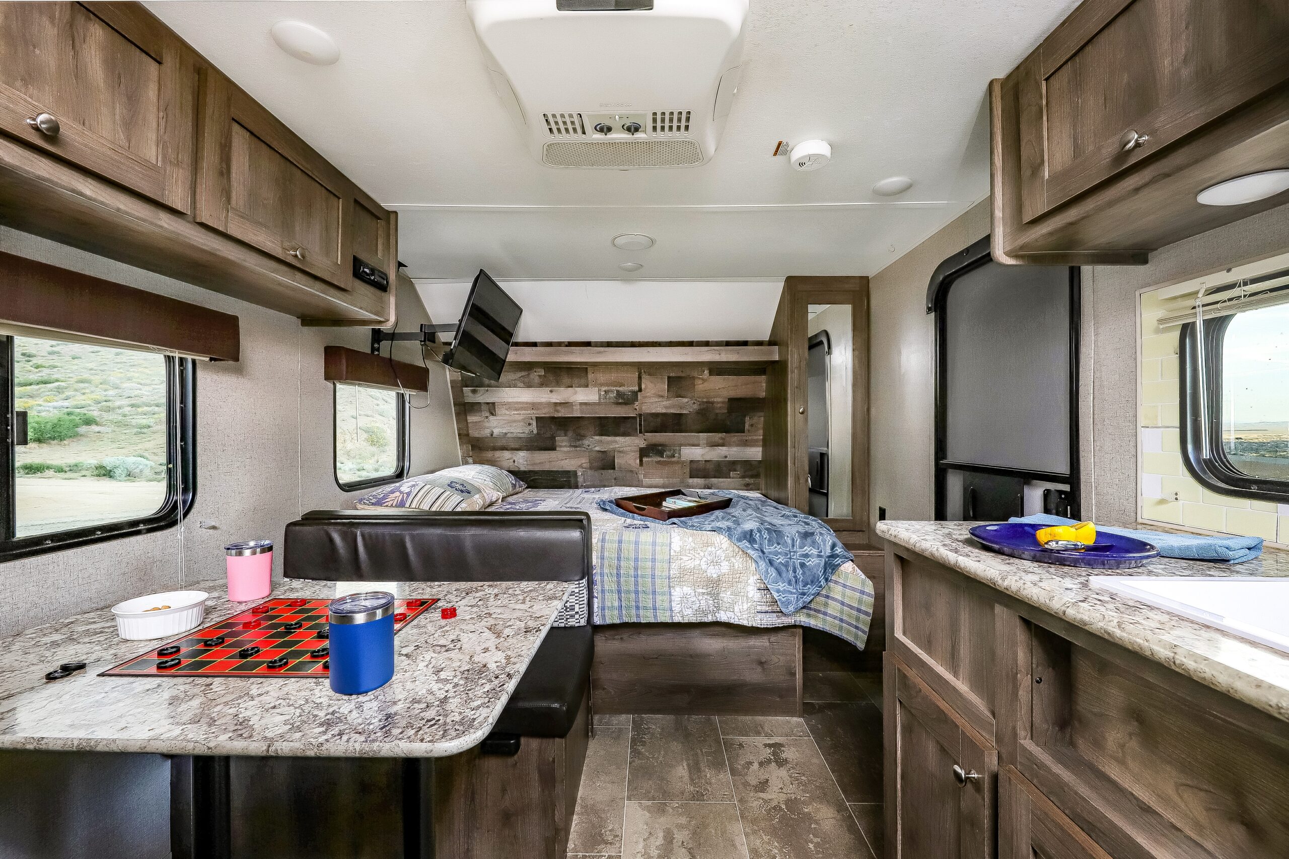 Cozy RV rental interior: bedroom with accent wall, dinette with checkers, and kitchen counter with desert views.. Aspen Trail LE 2020