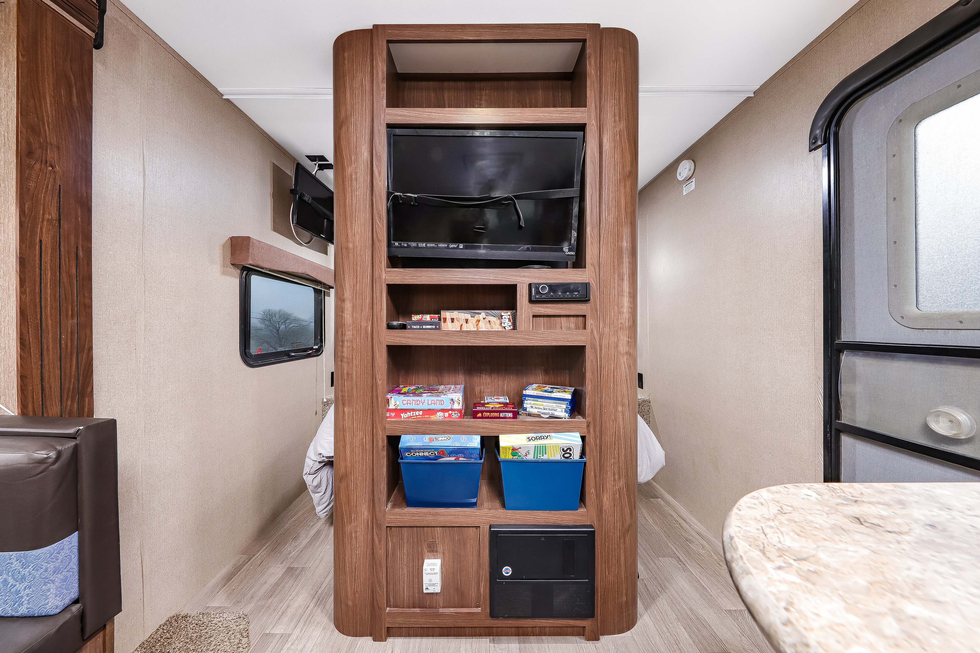 Cozy rv rental living space: an entertainment center with a TV, audio system, and shelves filled with board games like Jenga, Candy Land, and Connect 4.. Dutchmen Coleman Lantern 2017