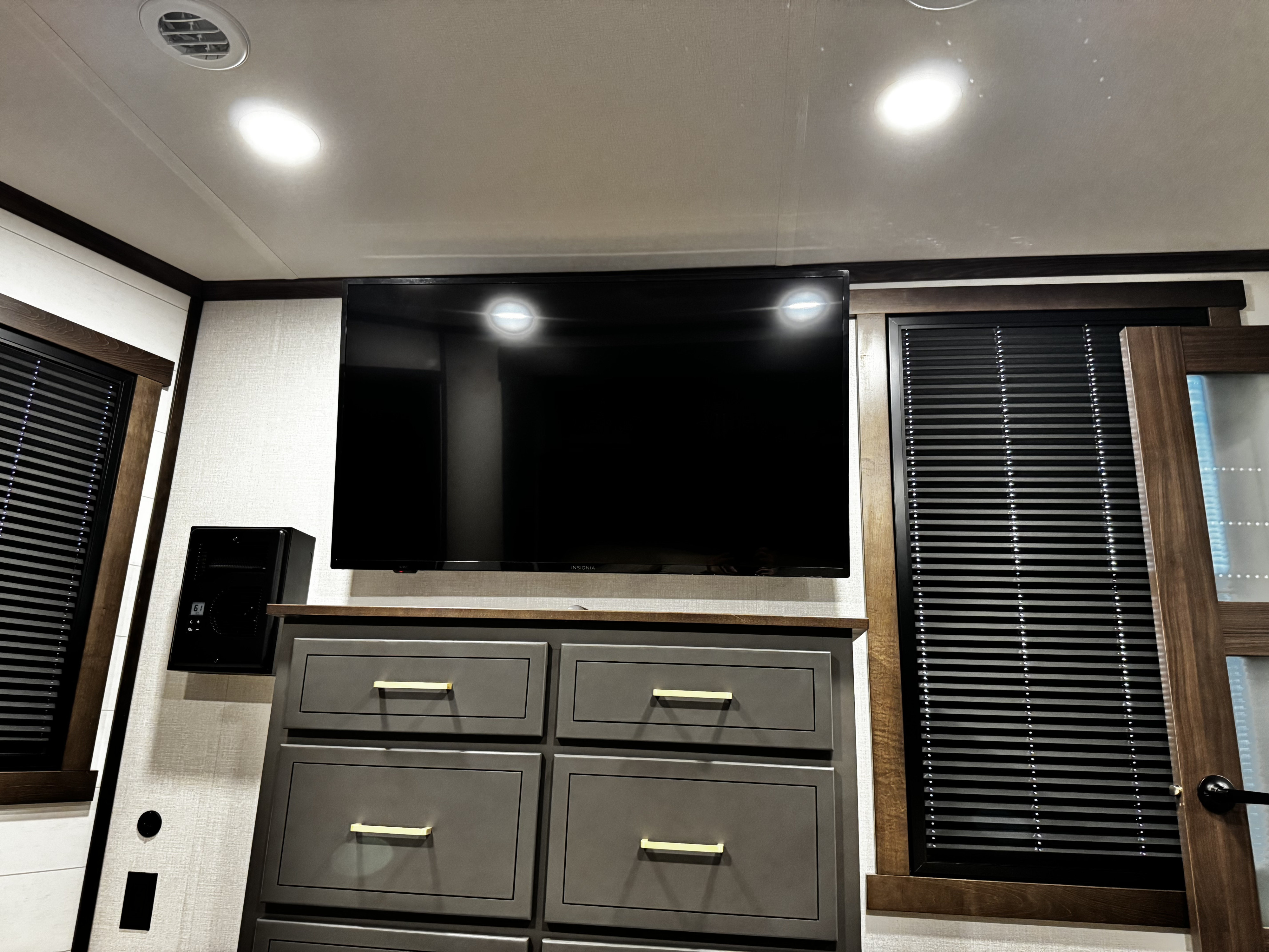 Inside an RV rental: features include a wall-mounted TV, dresser storage, and windows with blinds.. Forest River Cedar Creek Cottage 2025