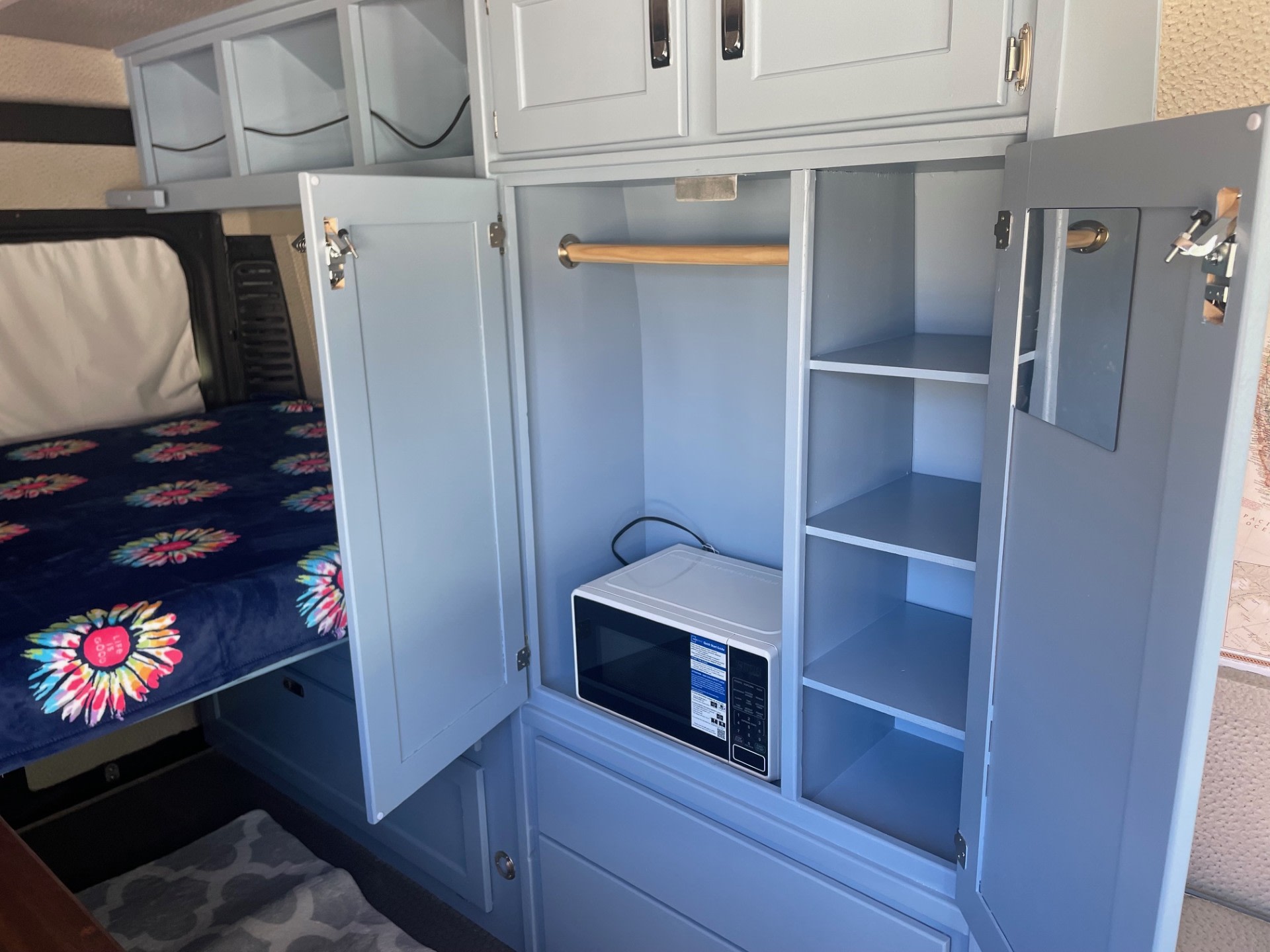 Explore this compact rv rental's custom light gray wardrobe, microwave, and comfy bed, designed for travel convenience.. Dodge Promaster Highroof 2019