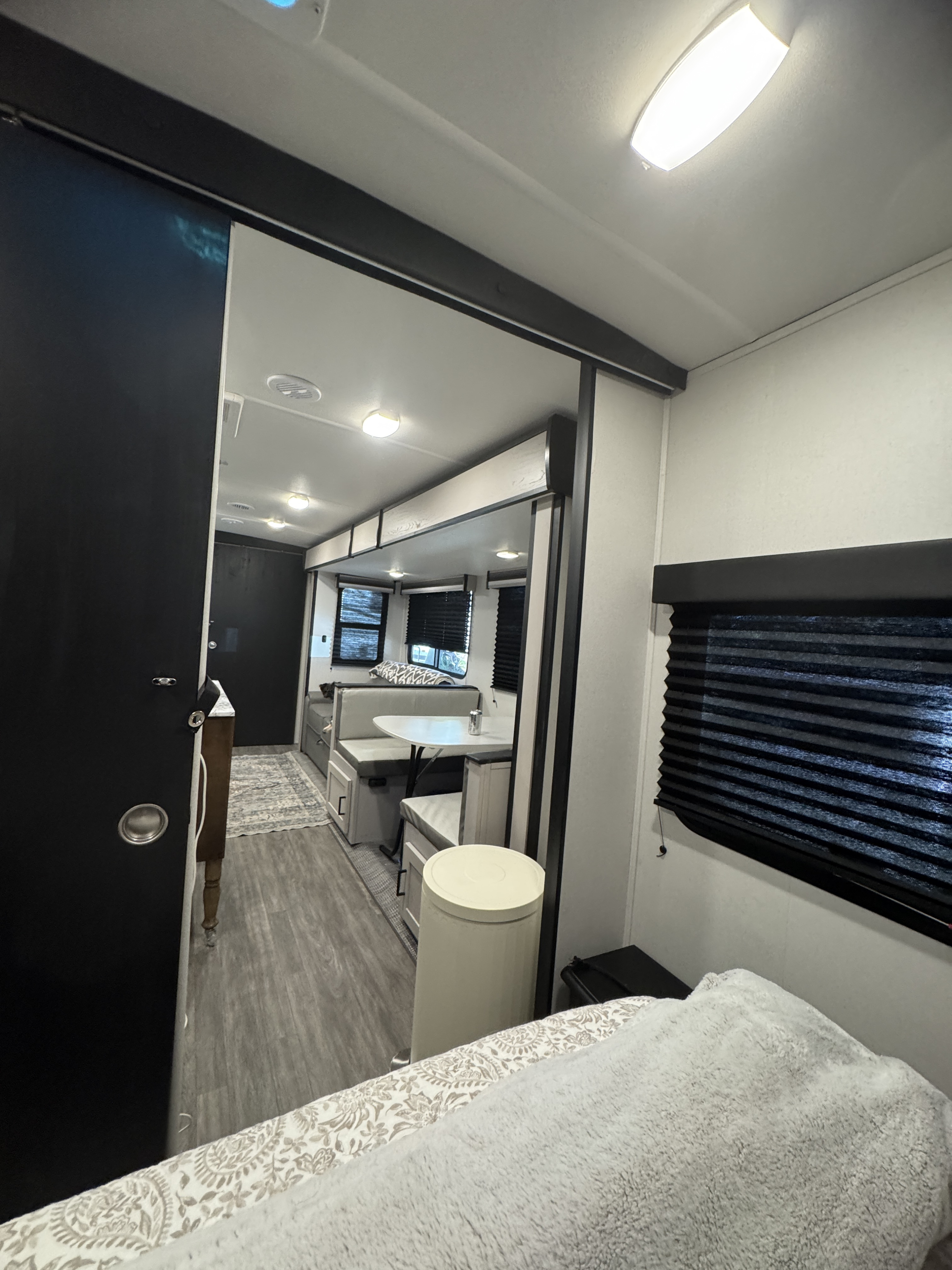 RV rental interior: cozy bed, sliding black door, and dinette with modern black-trimmed windows. Bright, functional space.. Heartland RVs Mallard 2024
