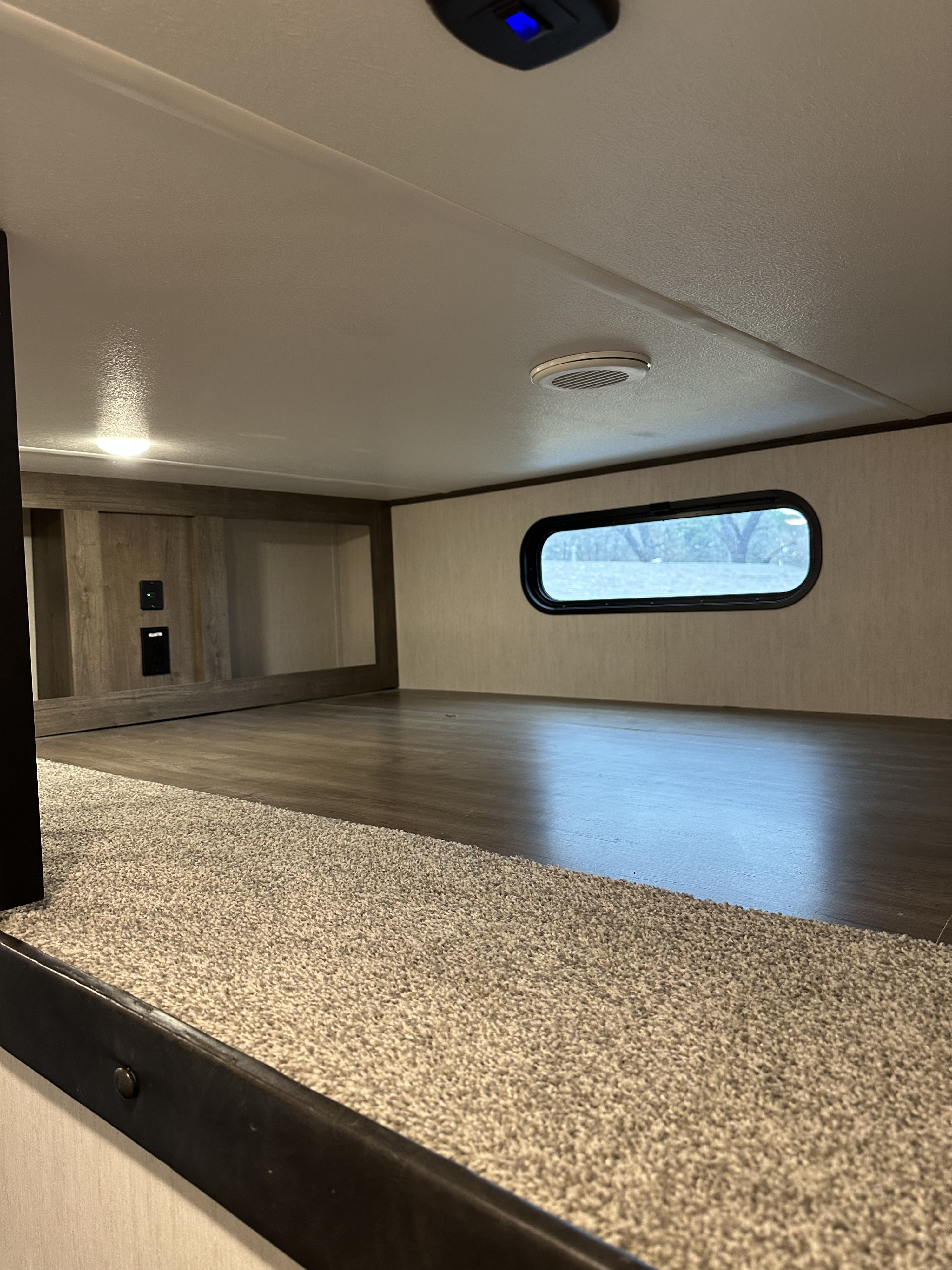 Spacious RV rental bunk area features wood-look flooring, built-in storage cubbies, and an oval window.. Forest River Sabre 2022