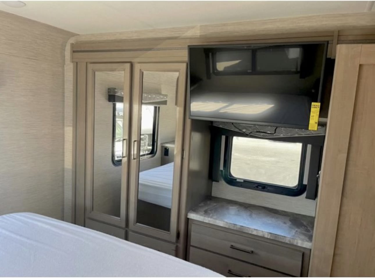RV rental bedroom with comfortable bed, mirrored wardrobe, TV, and dresser for cozy travels.. Thor Four Winds 2023