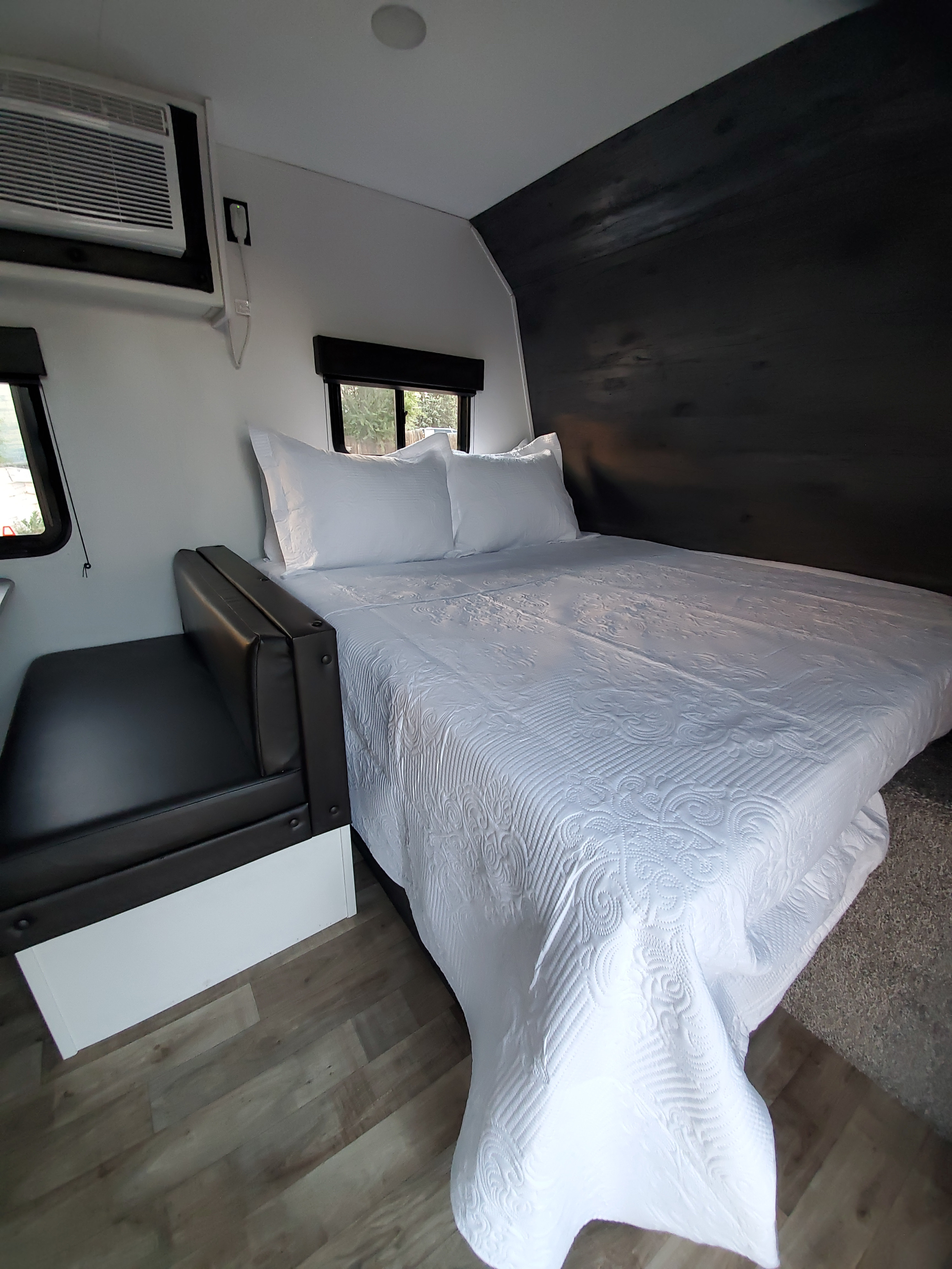 RV rental: Inside a clean RV bedroom. Features white bedding, AC, a black accent wall, and dinette seating.. Keystone RV Hideout 2021