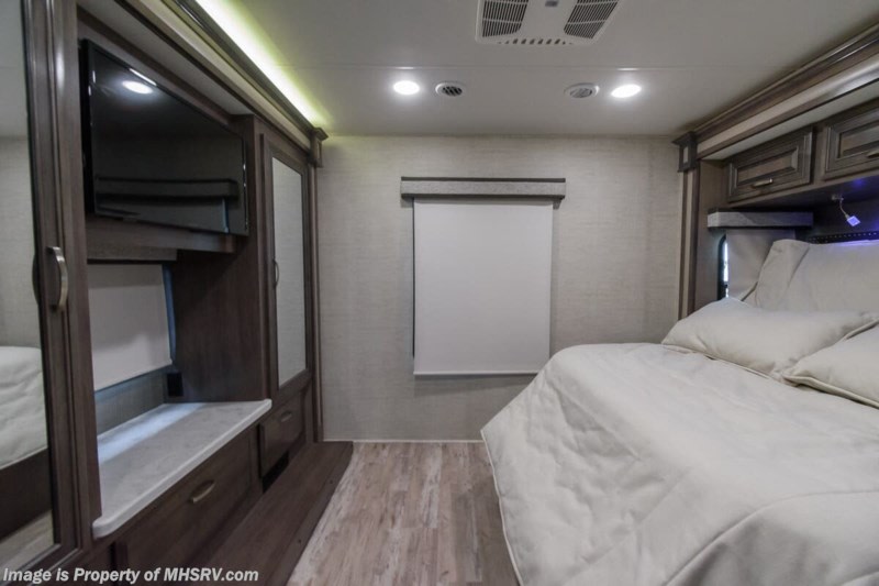 Comfortable RV rental bedroom features a large bed, built-in TV, and wardrobe with storage. Ideal for travel.. Entegra Coach Accolade 2023