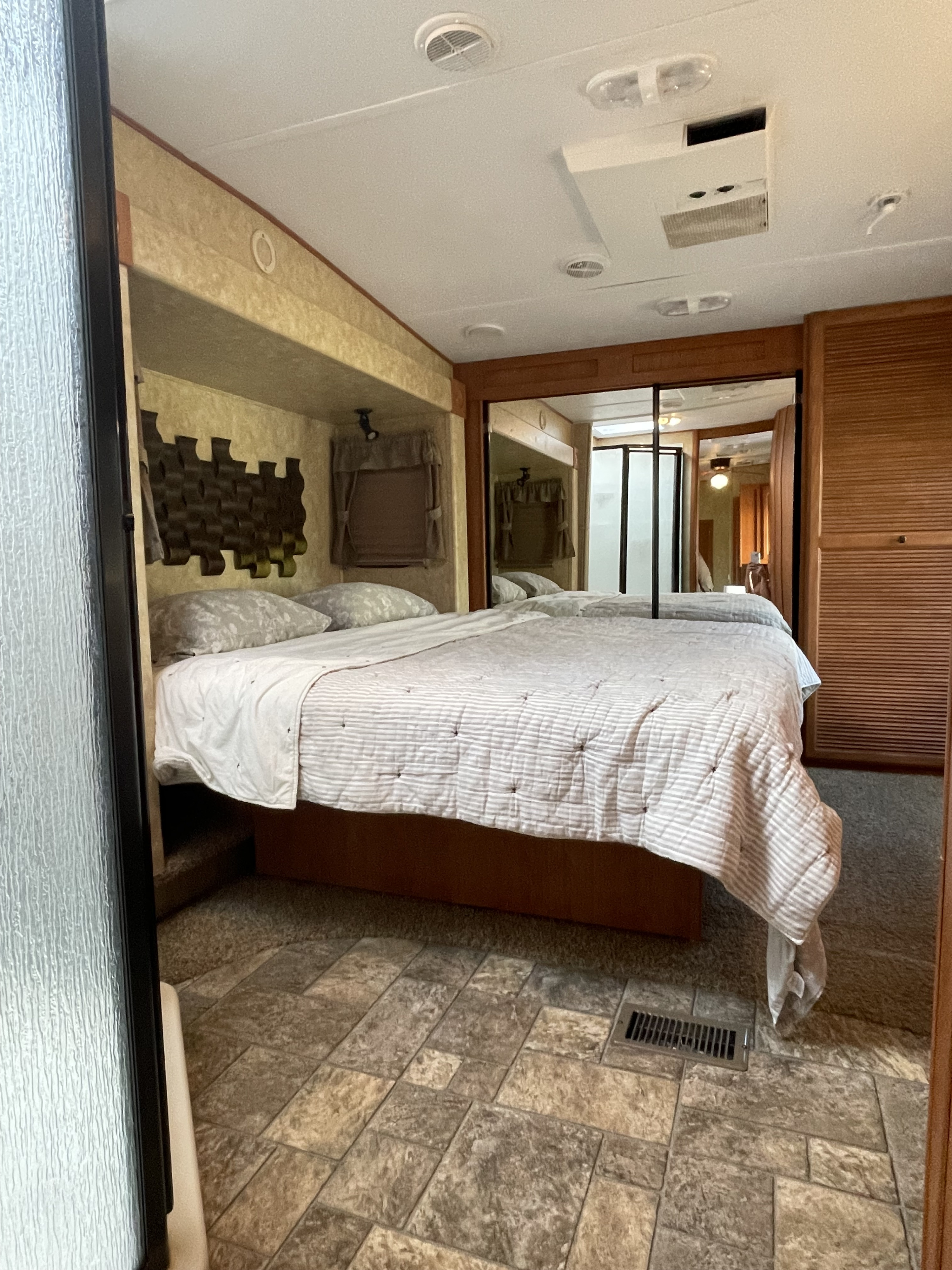 Comfortable rv rental bedroom featuring a striped bed, mirrored closet, and practical ceiling elements for a relaxing stay.. Forest River Sierra 2012