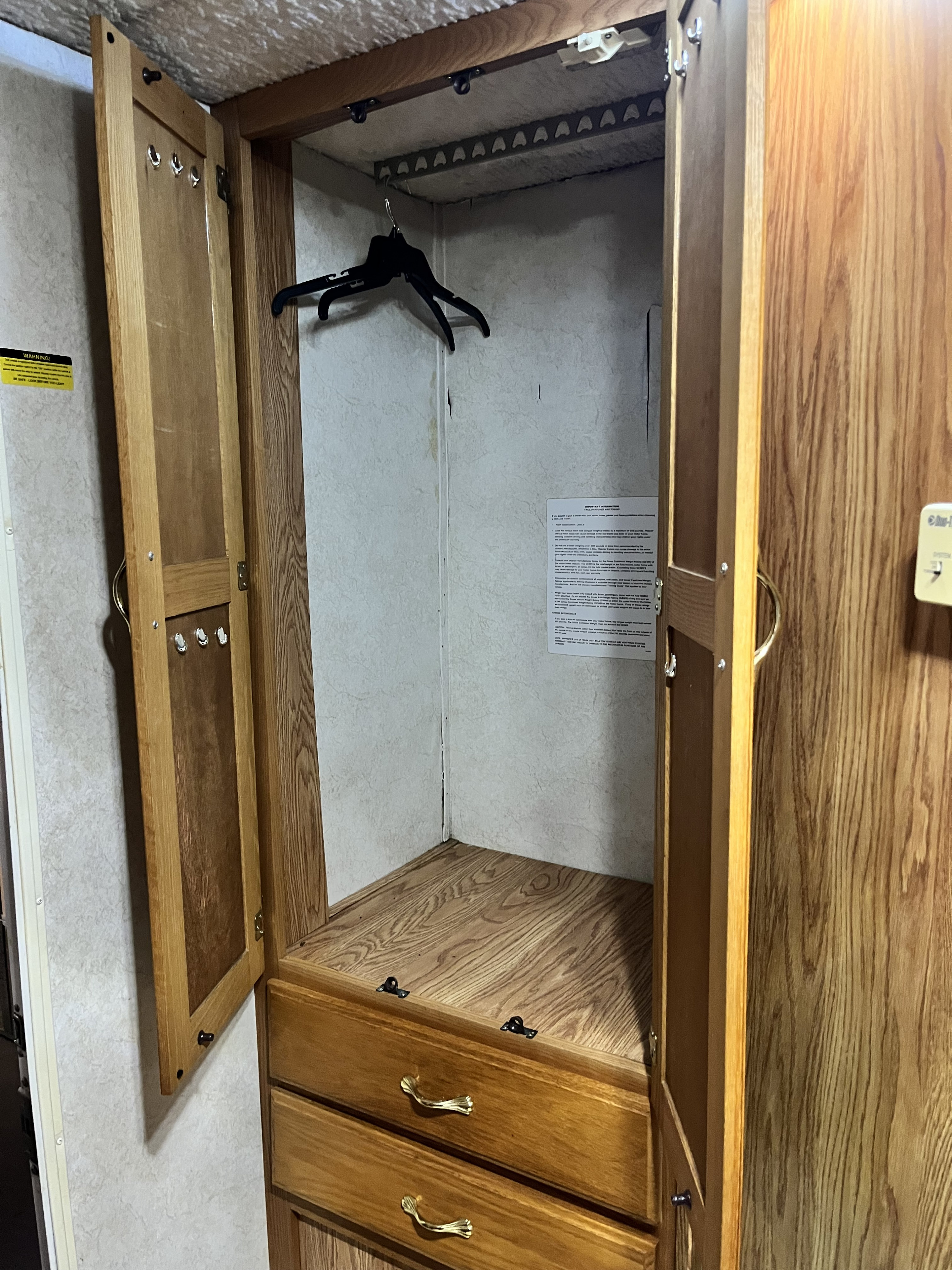 Inside this RV rental, find a functional wooden closet with a hanging rod, door hooks, and two drawers.. Gulfstream 5210 2003