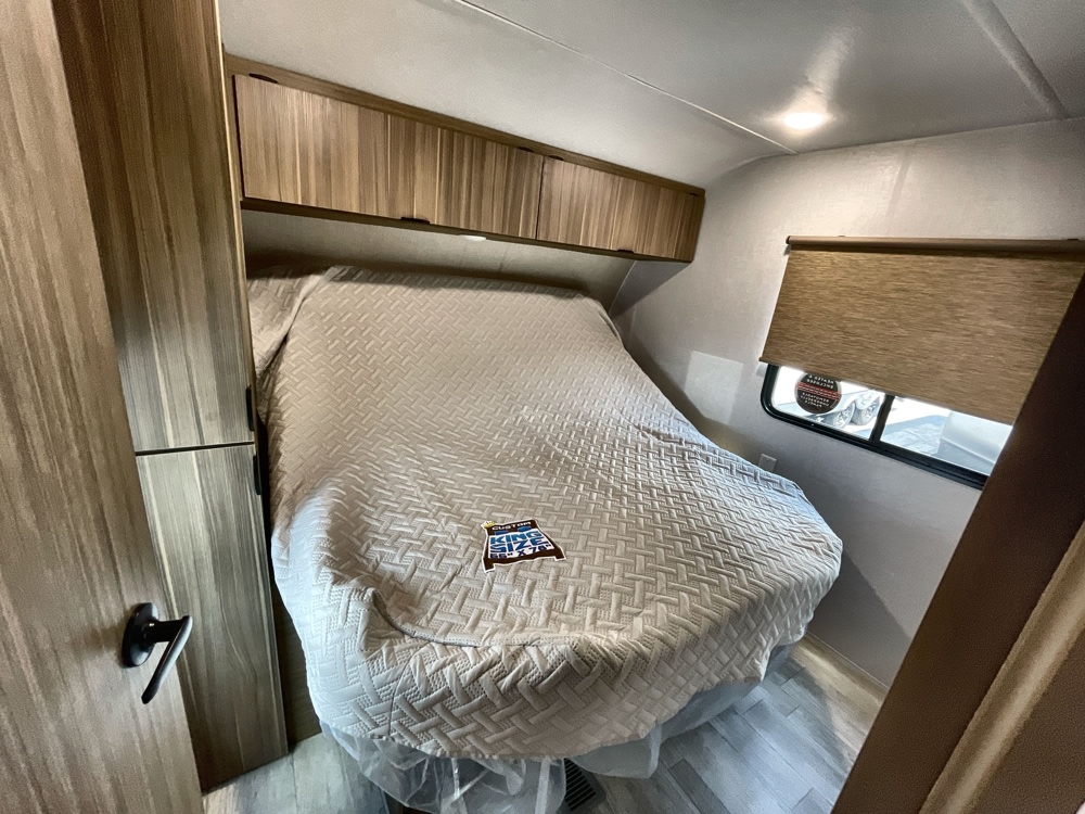 Spacious RV rental bedroom featuring a comfy king bed, overhead cabinets, and window with shade for restful travel.. Forest River Salem 2025