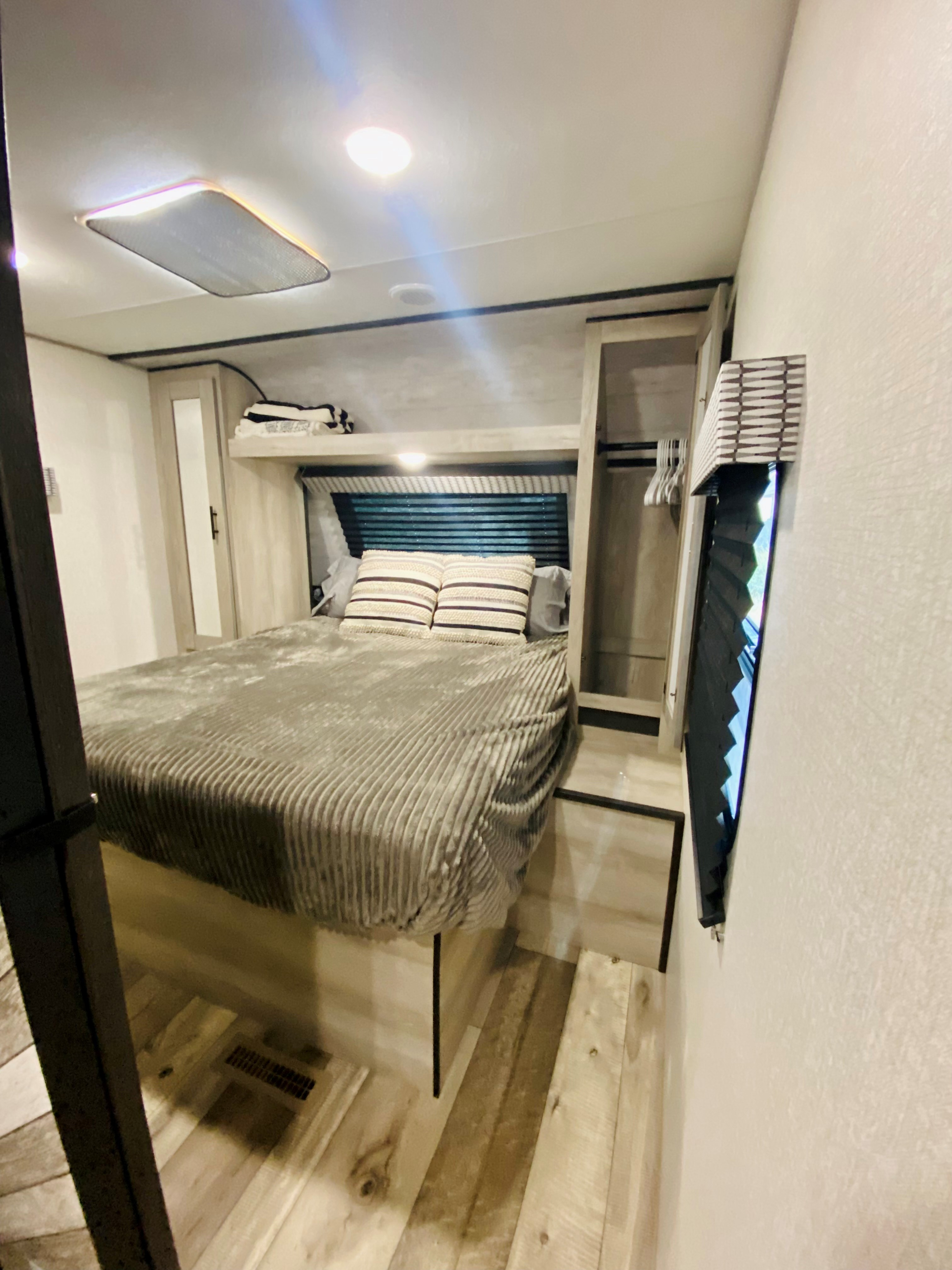 Bright RV rental bedroom: queen bed, built-in storage, window blinds, and overhead light. Perfect for travel.. Connect SE 2022