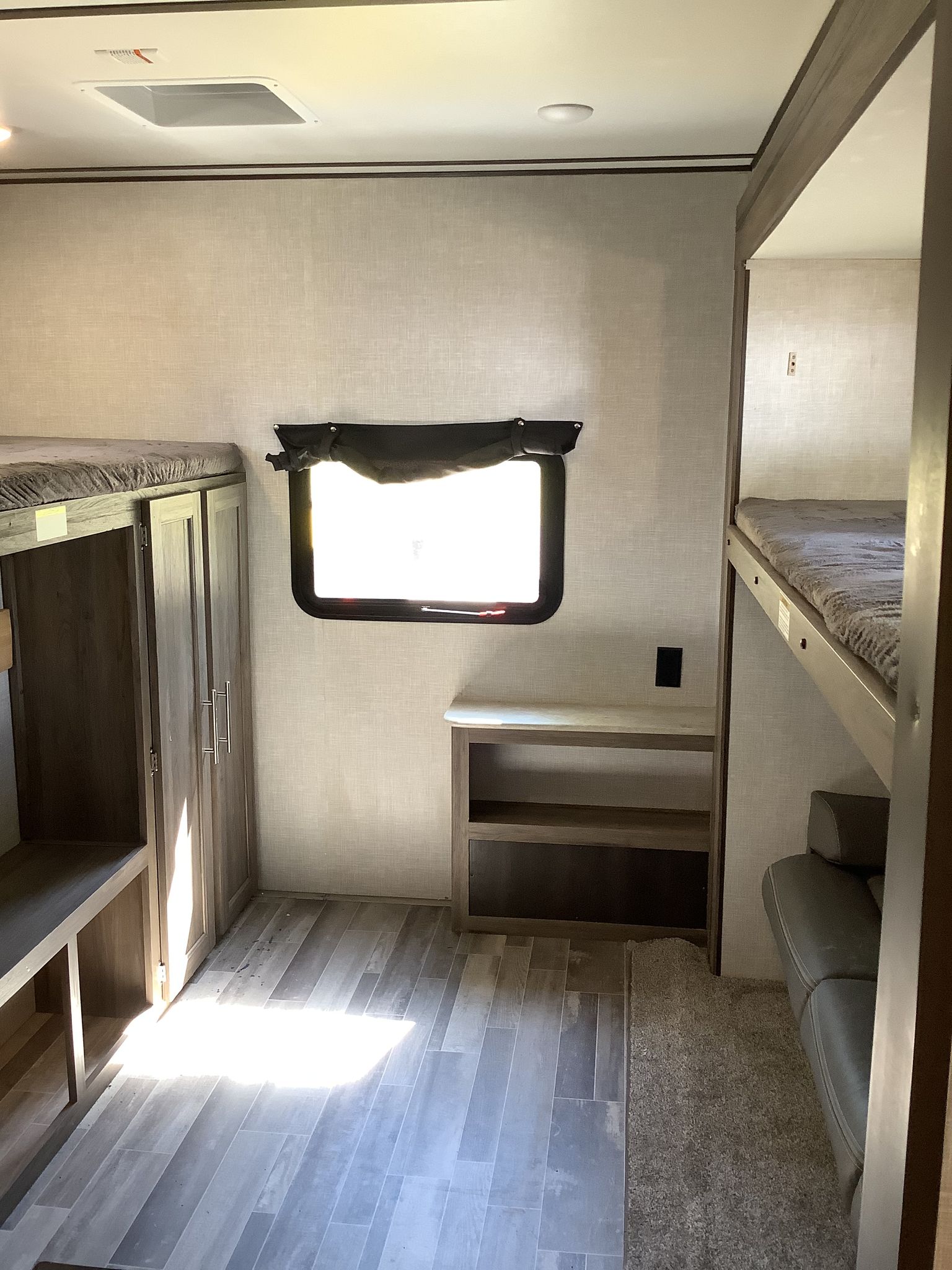 RV rental interior: modern bunk room featuring built-in storage, wood-look flooring, and a window with a blackout shade.. Crossroads RV Zinger 2021