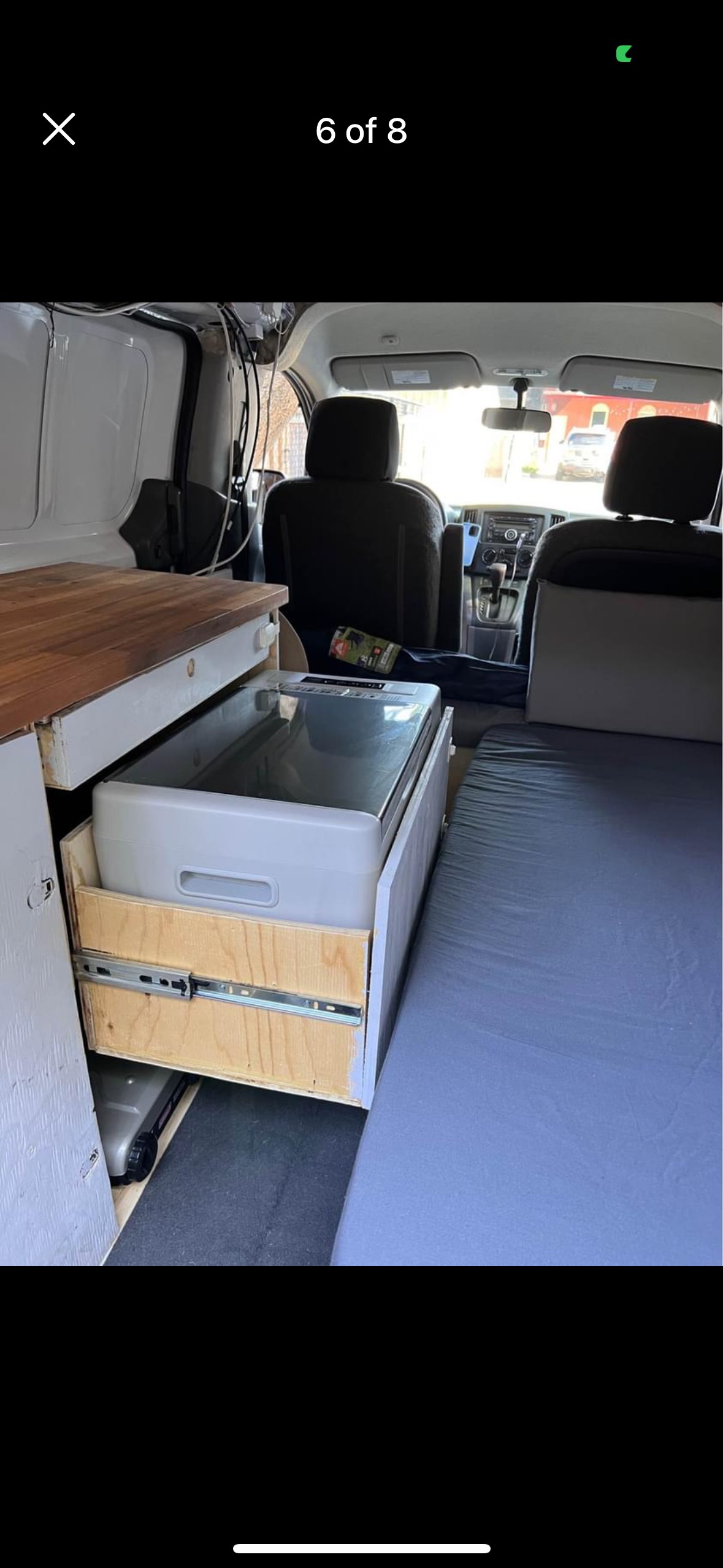 RV rental interior: custom camper van featuring a slide-out fridge, wooden countertop, and comfy bed.. Nissan NV200 2015