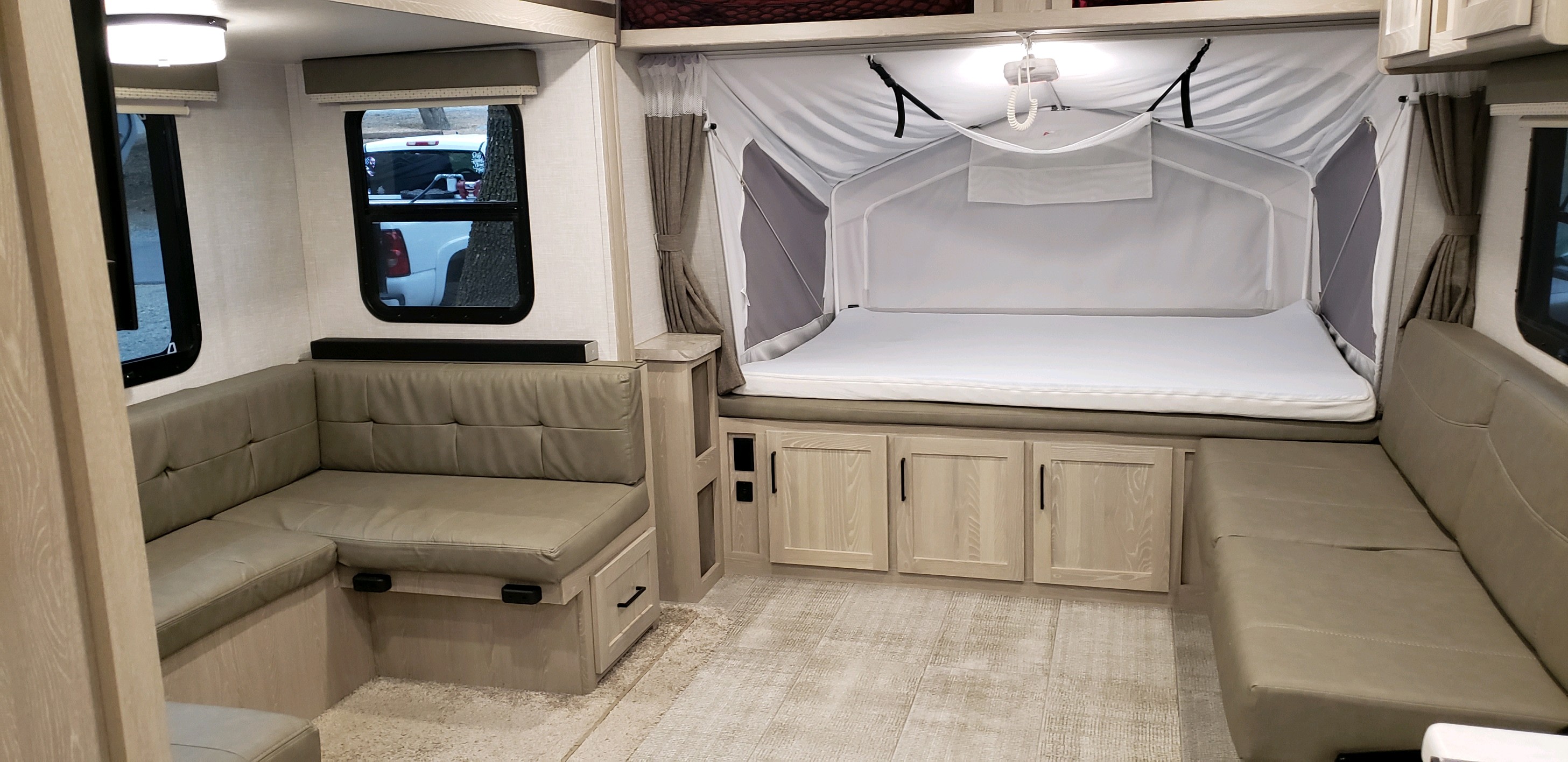 This RV rental interior features a spacious U-shaped dinette, a comfortable pop-out bunk bed, and light wood cabinetry.. Forest River Rockwood Roo 2021