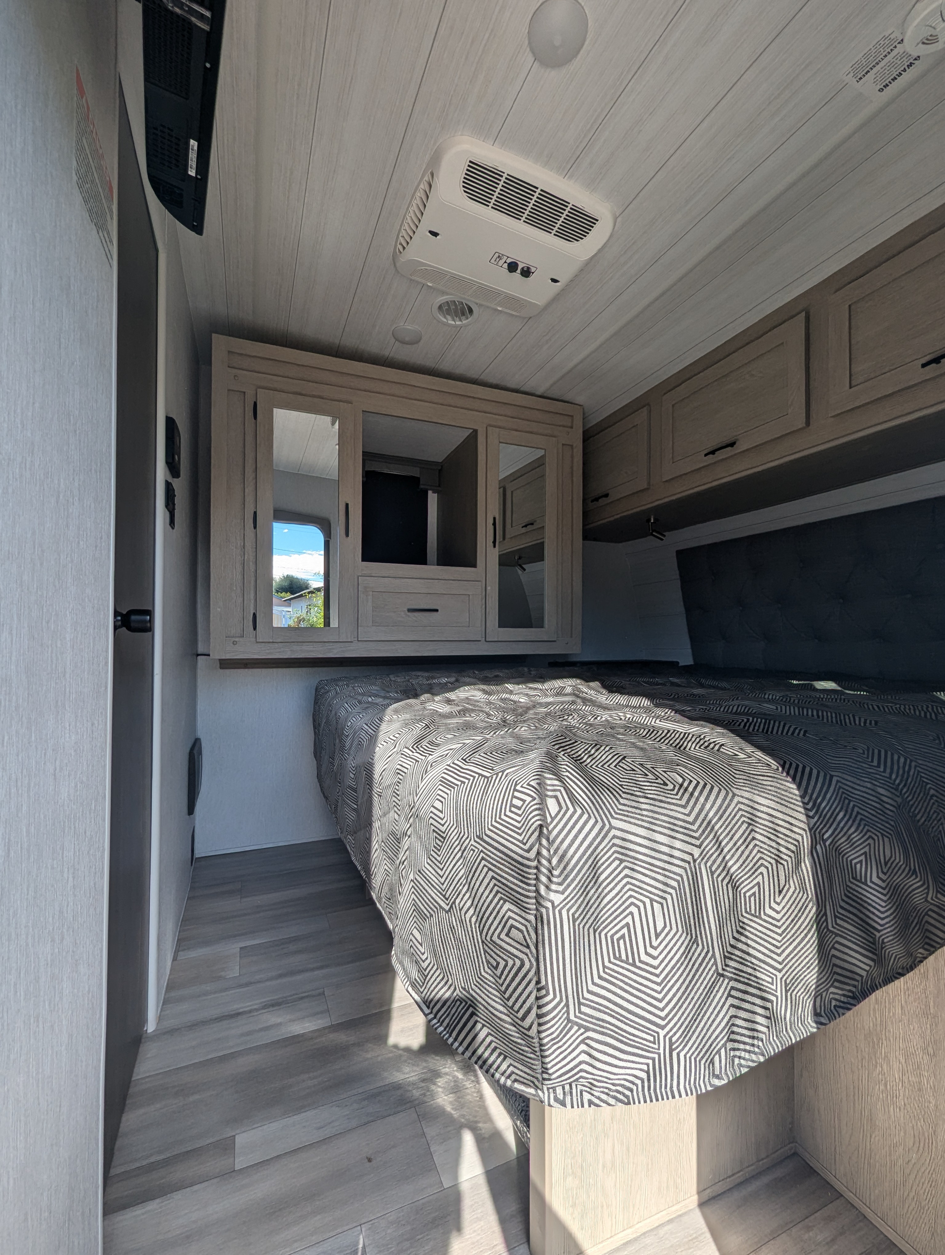 Step into comfort! This modern RV rental bedroom offers a cozy bed, ample storage, and AC for relaxing road trips.. Forest River Shockwave 2024