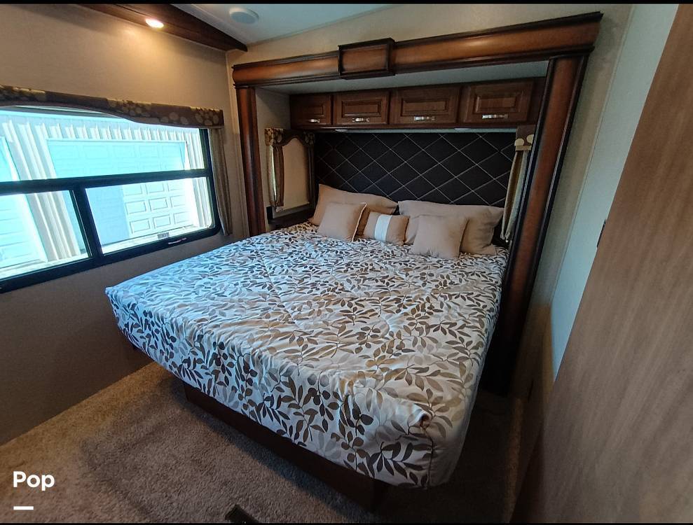 Comfortable RV rental bedroom featuring a bed with a patterned comforter, pillows, and a large window.. Keystone Montana 2018