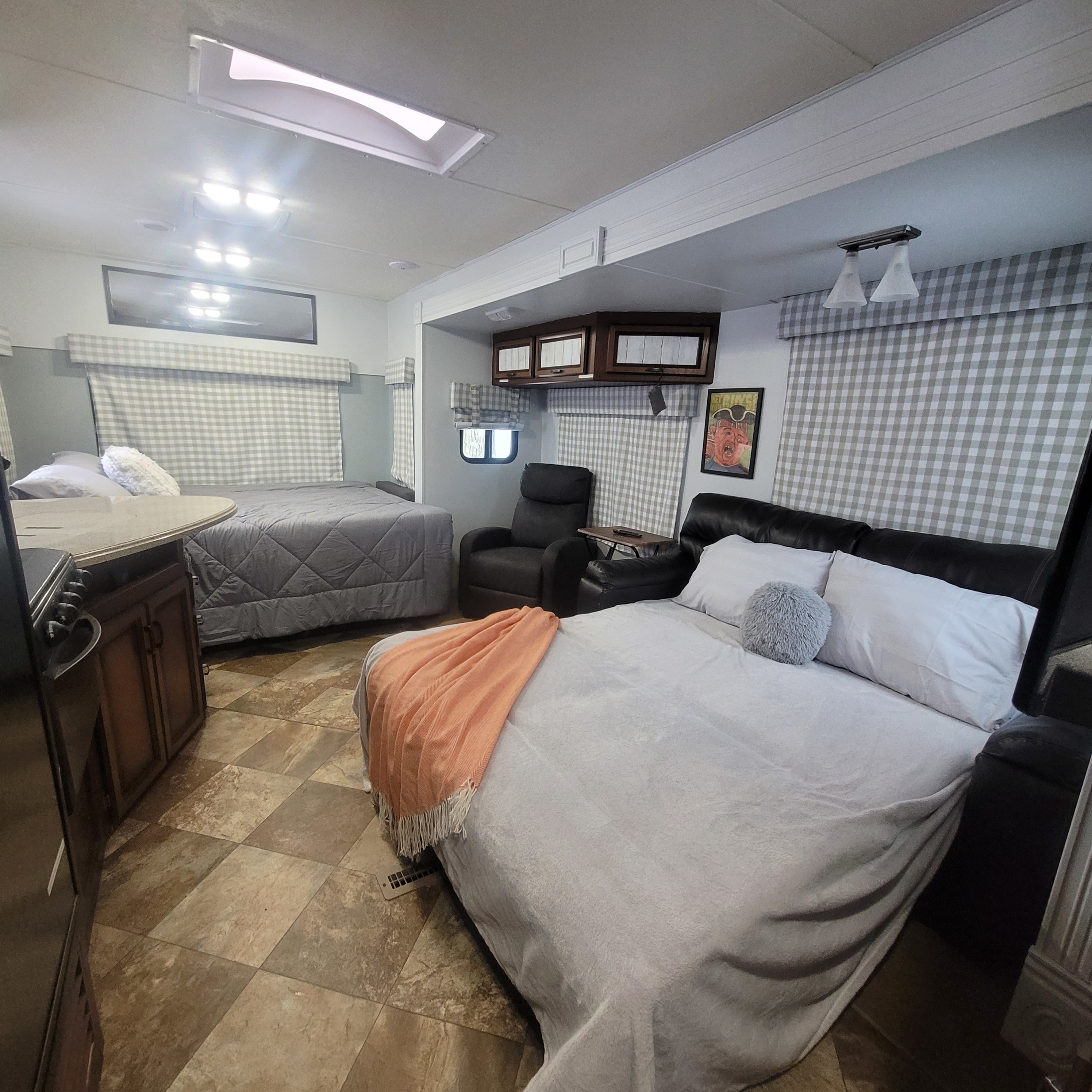 Cozy RV rental interior featuring two beds, recliner chairs, and a kitchenette. Perfect for a comfortable road trip.. Crossroads RV Zinger 2014