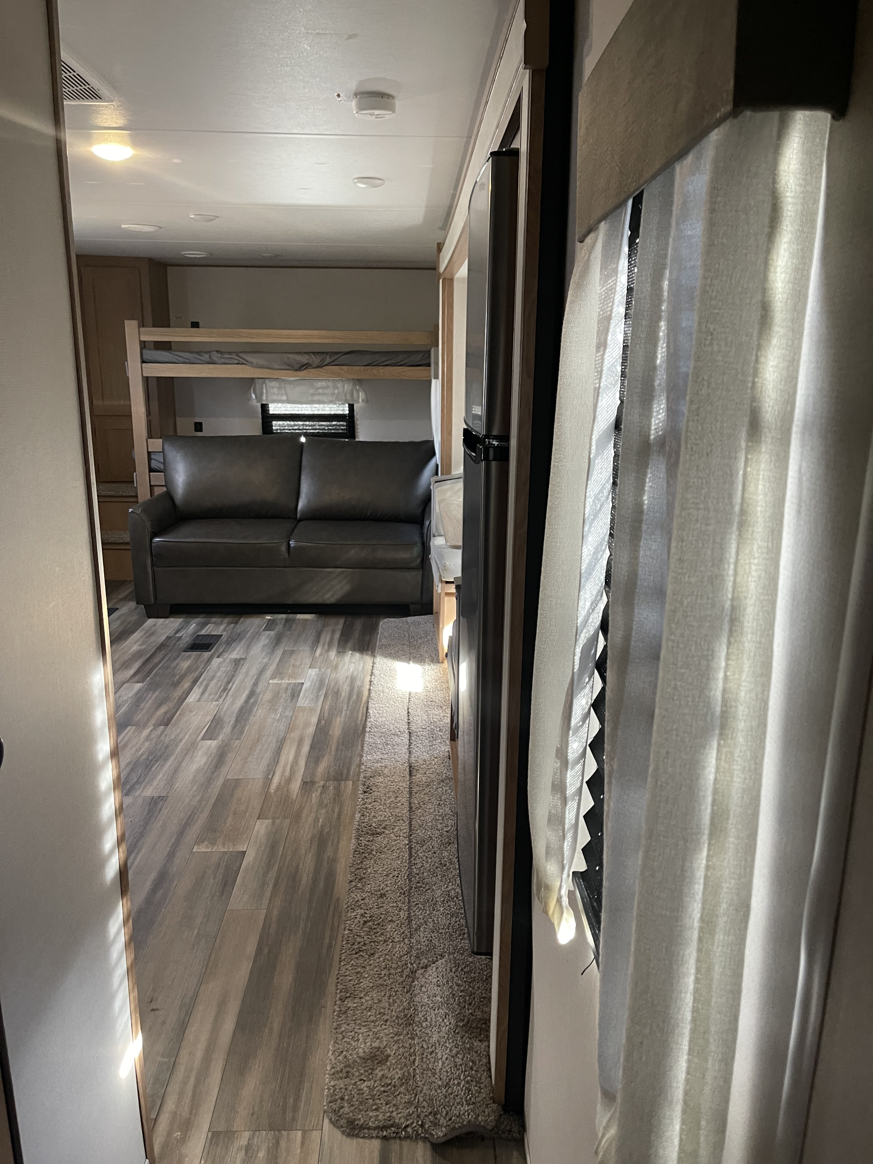 RV rental interior: comfortable sofa, bunk beds, and refrigerator in a bright, modern living space.. Avenger M28-BHS 2022