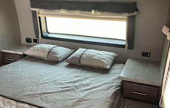 Comfort awaits in this RV rental bedroom, featuring a large bed, nightstands, and window for serene travels.. Forest River Rockwood Ultra Lite 2020