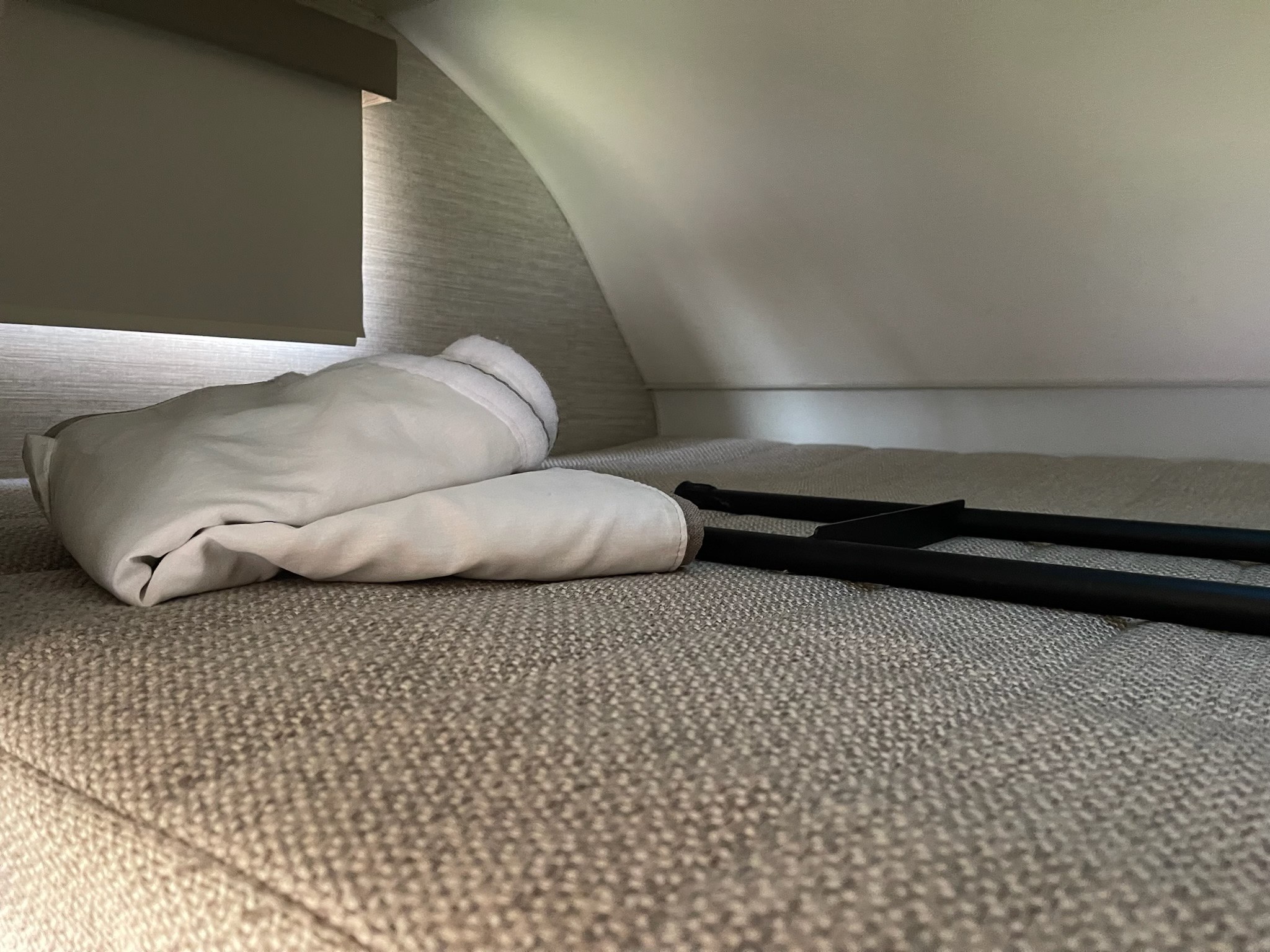 RV rental interior: a soft bunk bed with white bedding, a privacy blind, and access ladder/rail.. Winnebago Minnie Winnie 2022