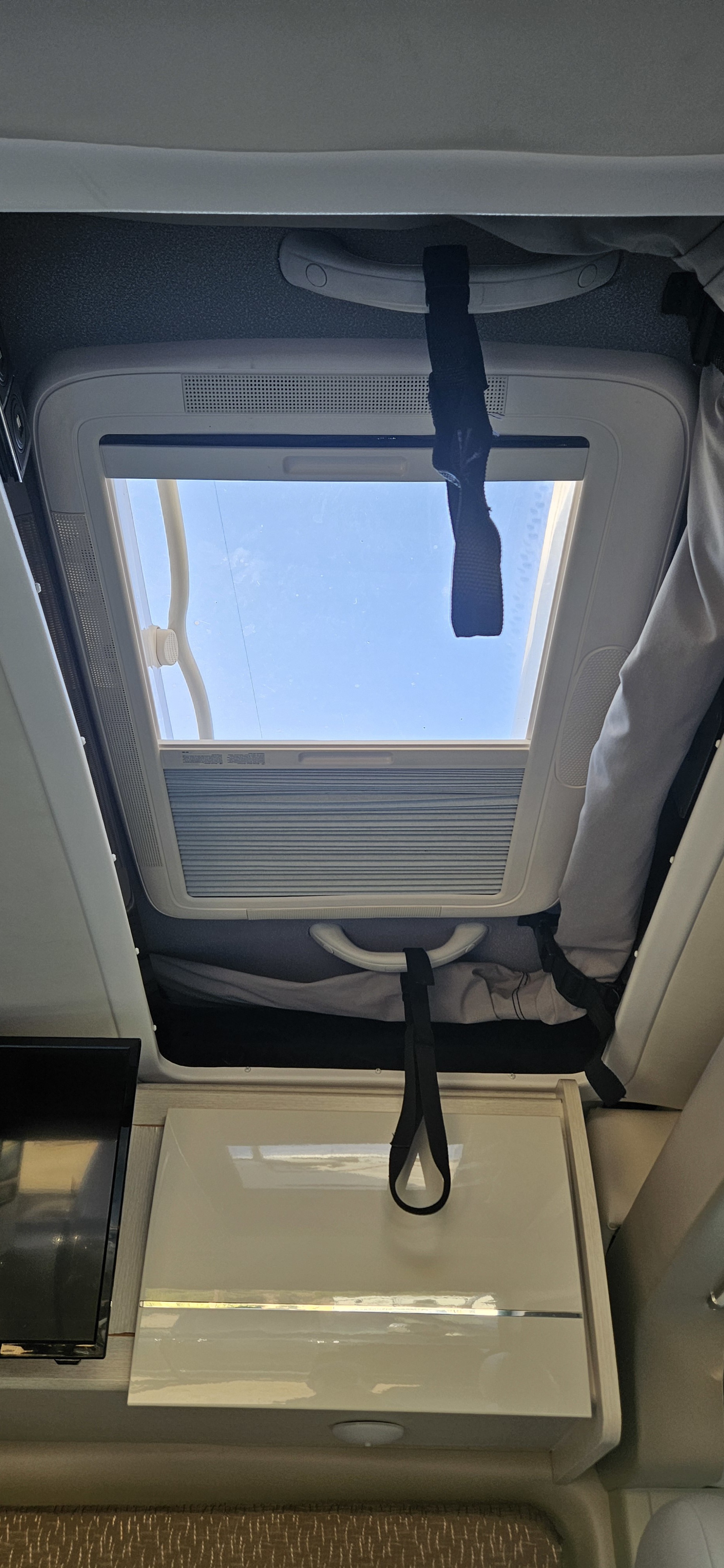 Inside an RV rental: Enjoy the view through the roof skylight. Features include overhead cabinets & a TV, perfect for travel.. Thor Tellaro 2022