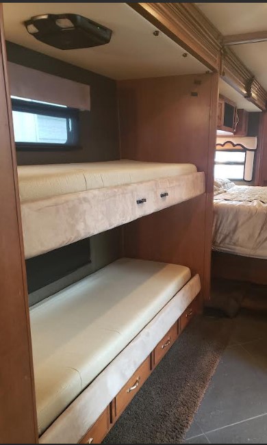 RV rental with built-in bunk beds, complete with mattresses & under-bunk storage drawers. Main bedroom visible in background.. Fleetwood Discovery 2013