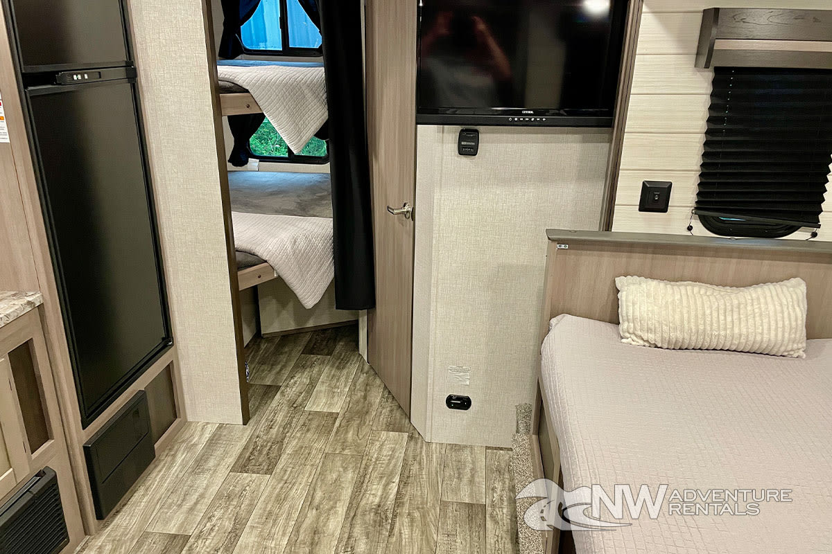 Inside this RV rental: master bed, TV, refrigerator, and a separate bunk bed area for extra sleeping space.. Crossroads Sunset Trail 2022