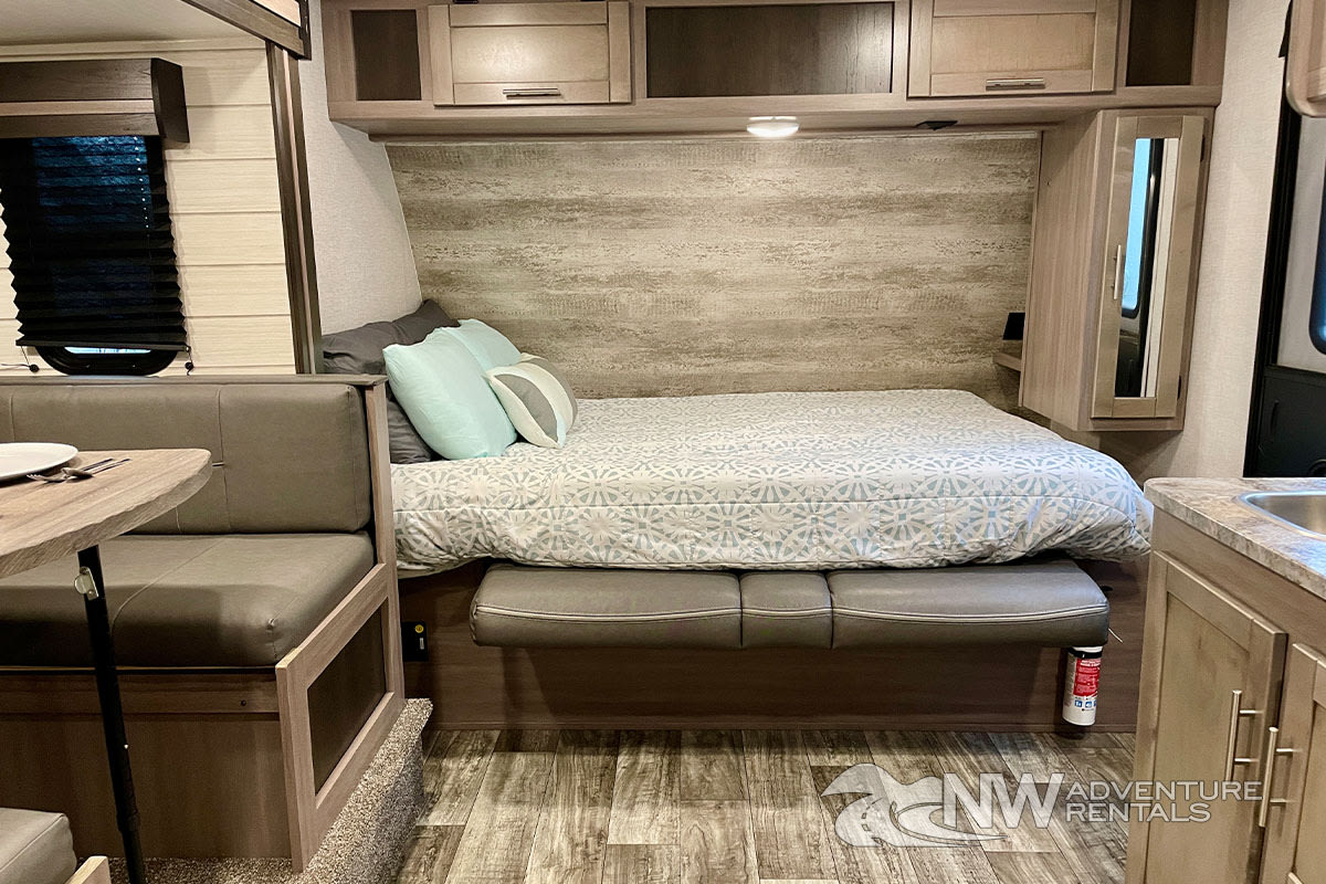 Cozy RV rental interior with bed, dining booth, and kitchenette area, perfect for travel adventures.. Crossroads Sunset Trail 2022