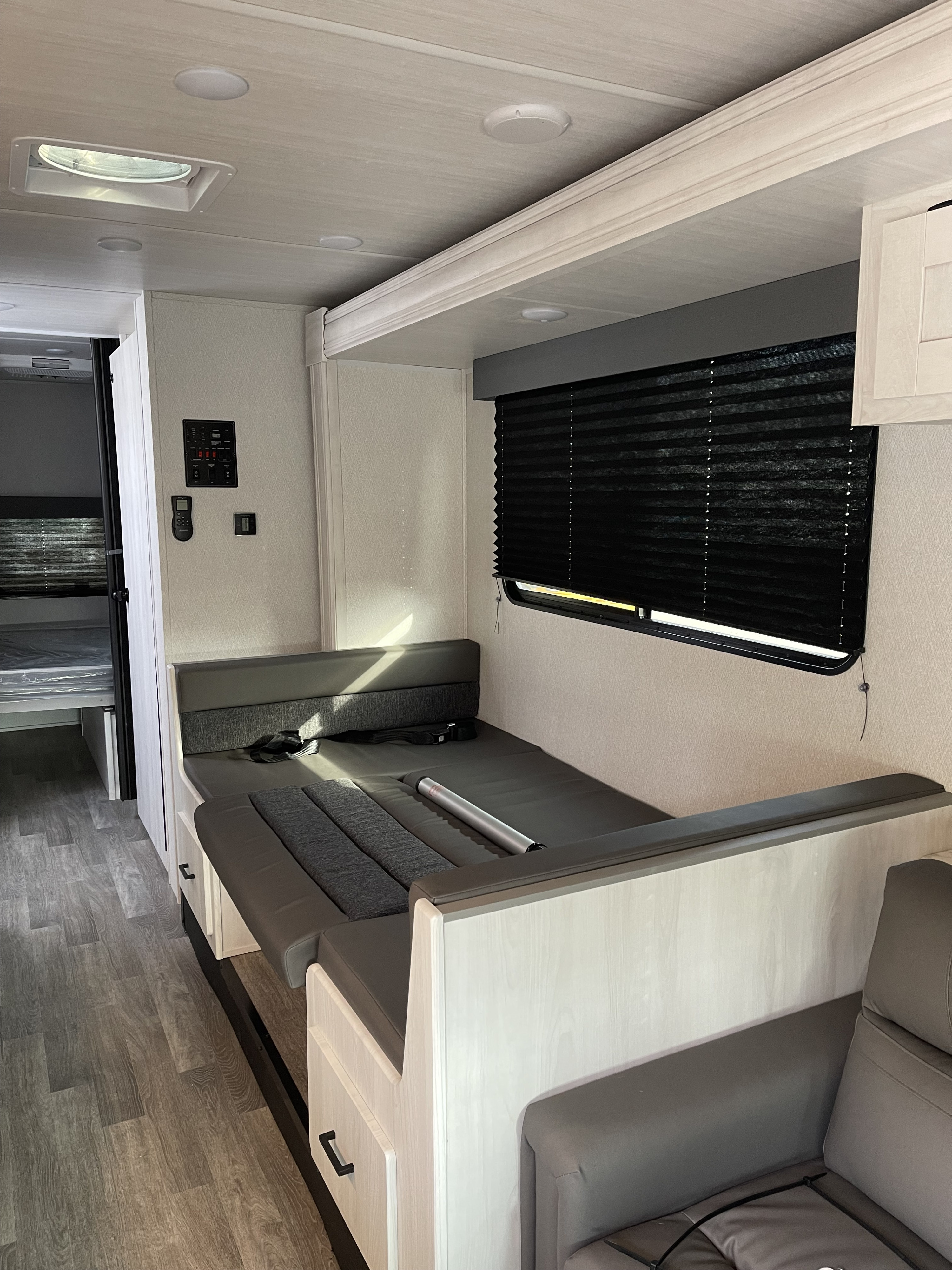 RV rental interior: A light-filled space with a convertible dinette/bed, bunk beds, modern control panel, and wood-look flooring.. Ford E450 2023