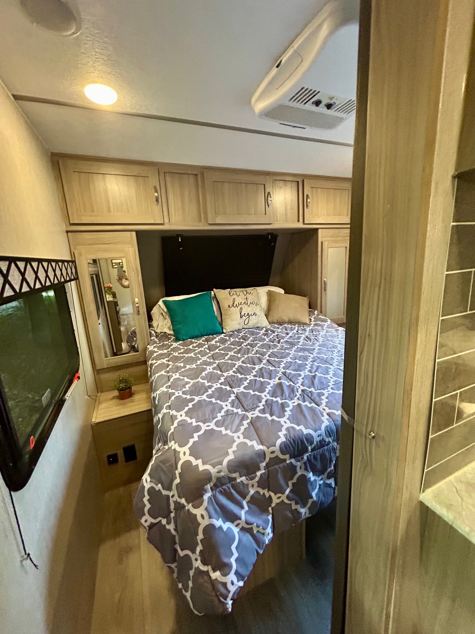 Cozy RV rental bedroom with a queen bed, overhead storage, mounted TV, and AC unit, ready for your next adventure.. Coachmen Freedom Express 287 BHDS 2021