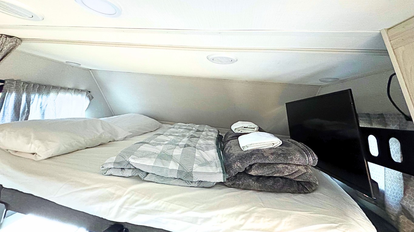 Cozy RV rental cab-over bunk featuring a comfortable bed, pillows, blankets, and TV for relaxing travels.. Forest River Forester 2022