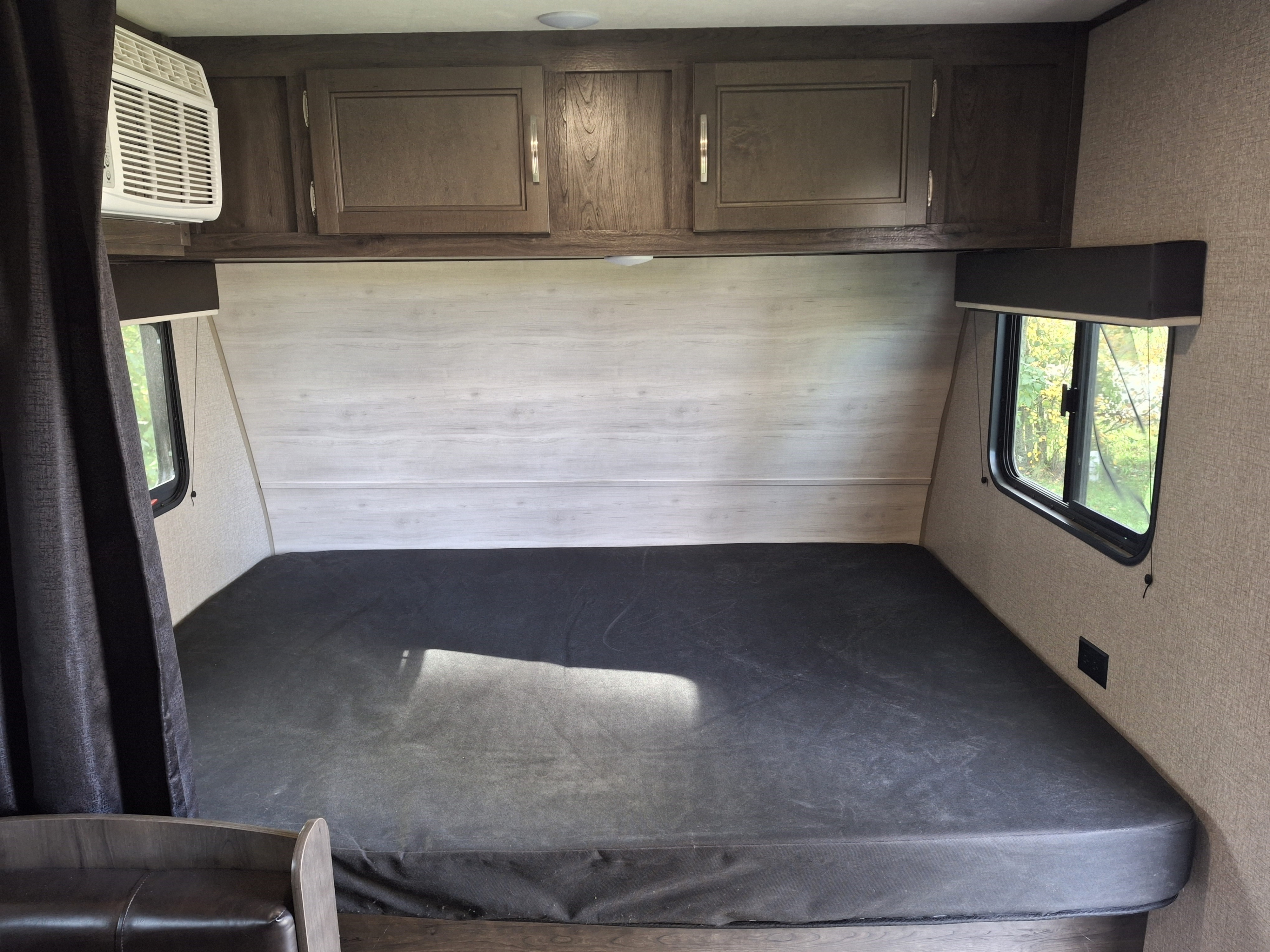 RV rental interior: Shows a large bed, overhead cabinets, and an AC unit, offering a comfortable sleeping space.. Jayco Jay Feather 2022