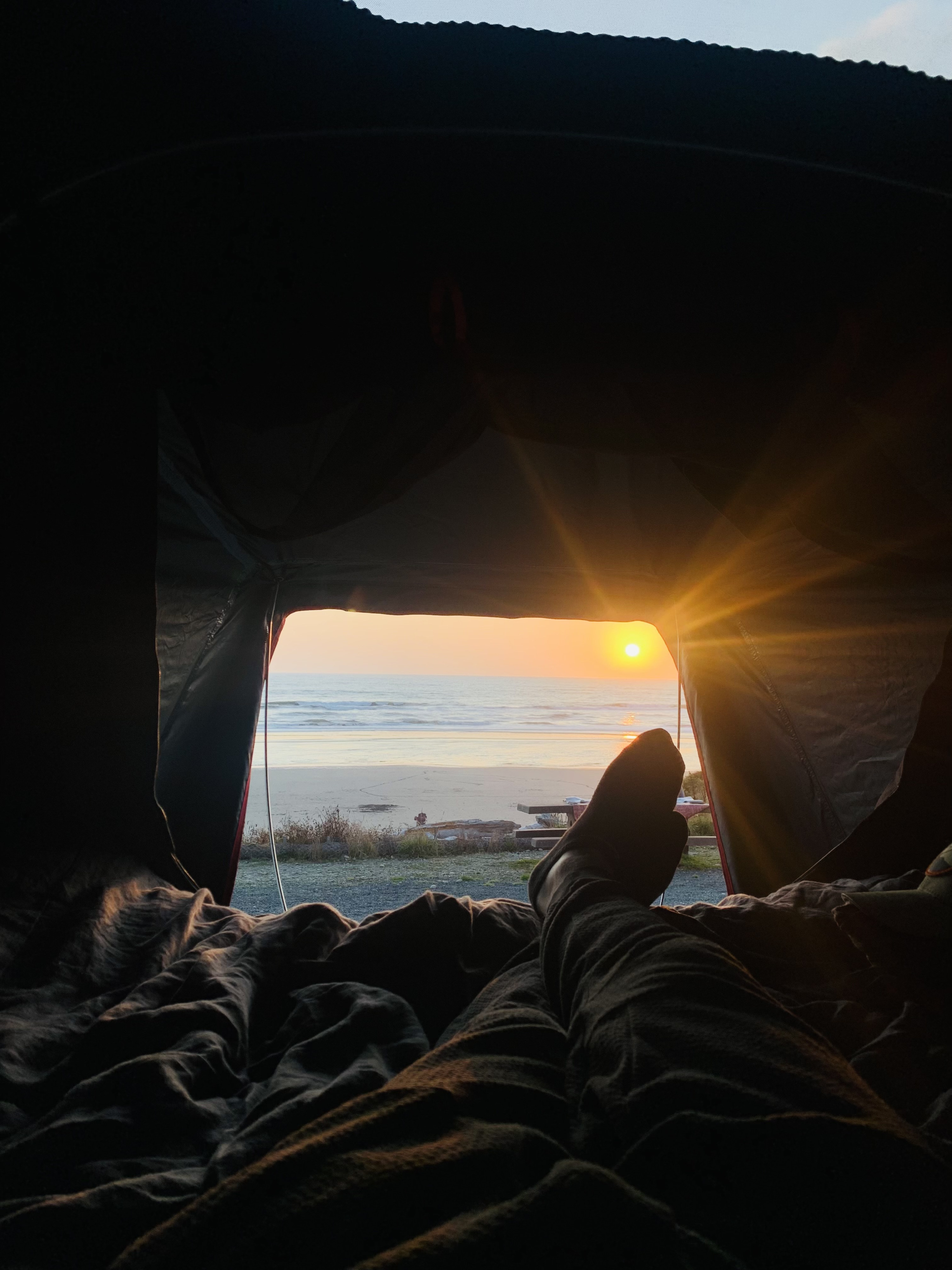 Cozy RV rental sunrise view: feet propped up, watching the golden sun rise over a tranquil beach and ocean.. Toyota Tacoma TRD-Pro 2020