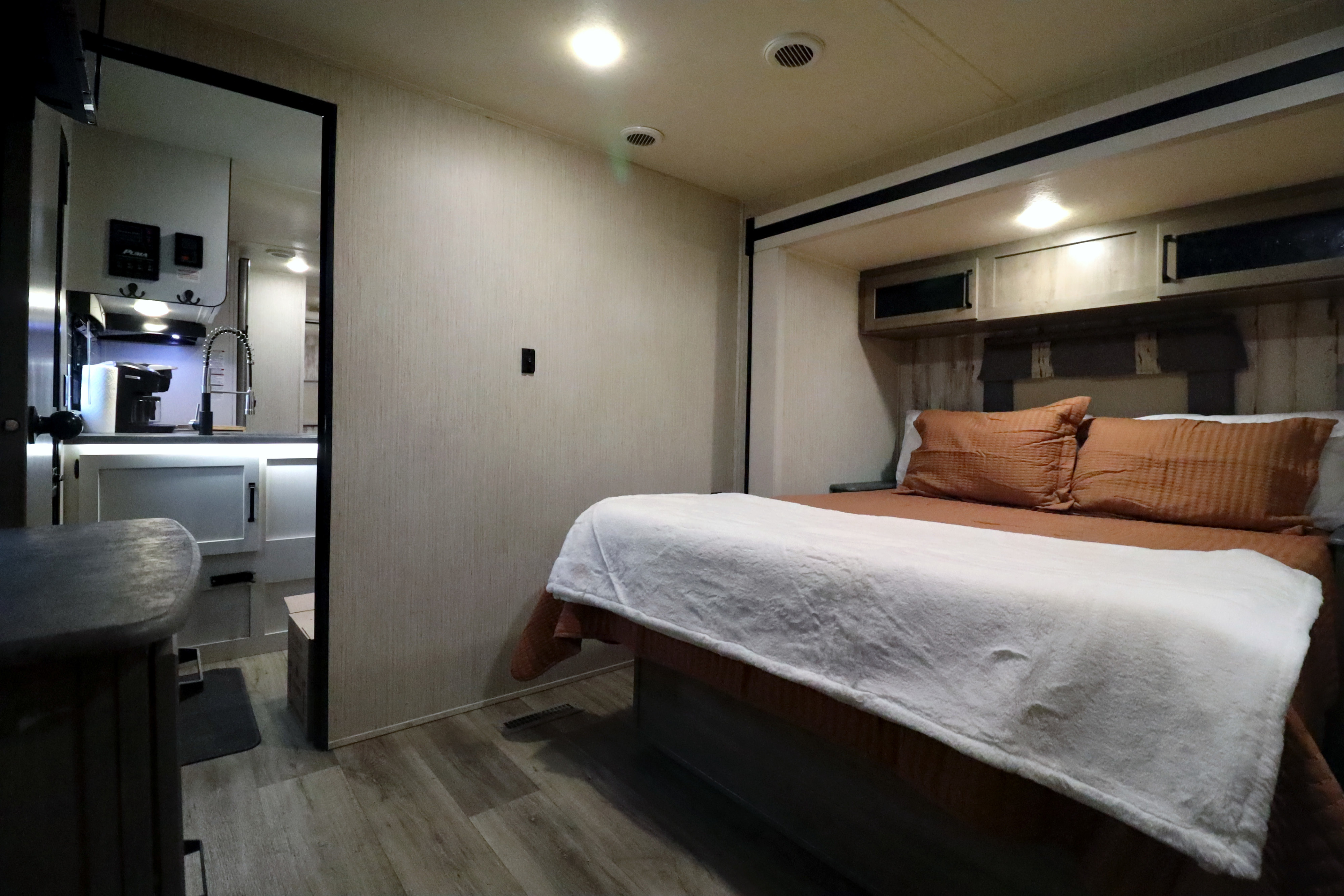 Cozy RV rental bedroom with warm lighting and a view into the equipped kitchen, ideal for travel.. Palomino Puma 32RBFQ2 2022