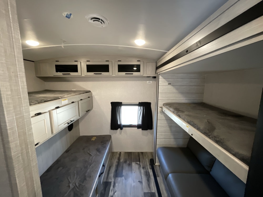 RV rental bunkhouse interior: Two sets of bunk beds, lower sofa & bench, and overhead storage.. Crossroads RV Sunset Trail Super Lite 2023