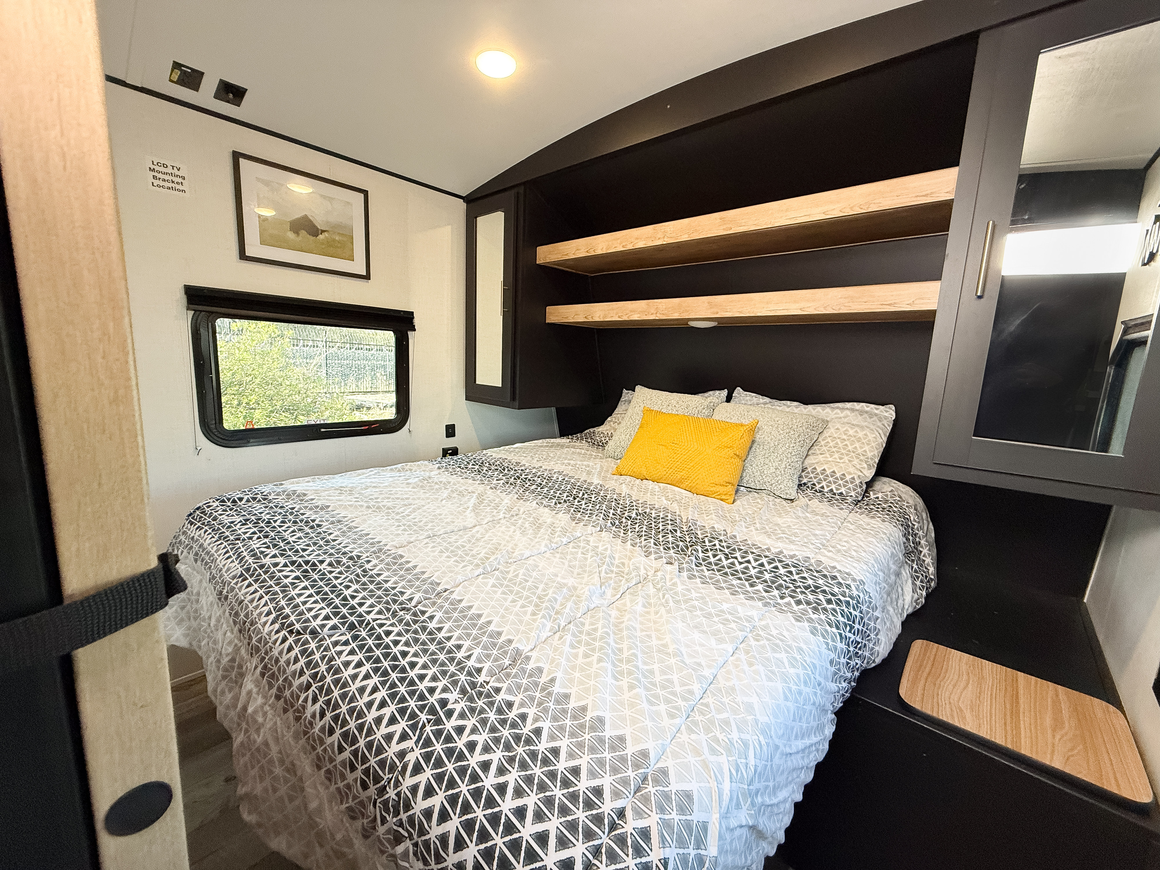 Experience comfort in this modern RV rental bedroom. Features a cozy bed, sleek dark storage, and a bright window for a relaxing trip.. Keystone Springdale 2024