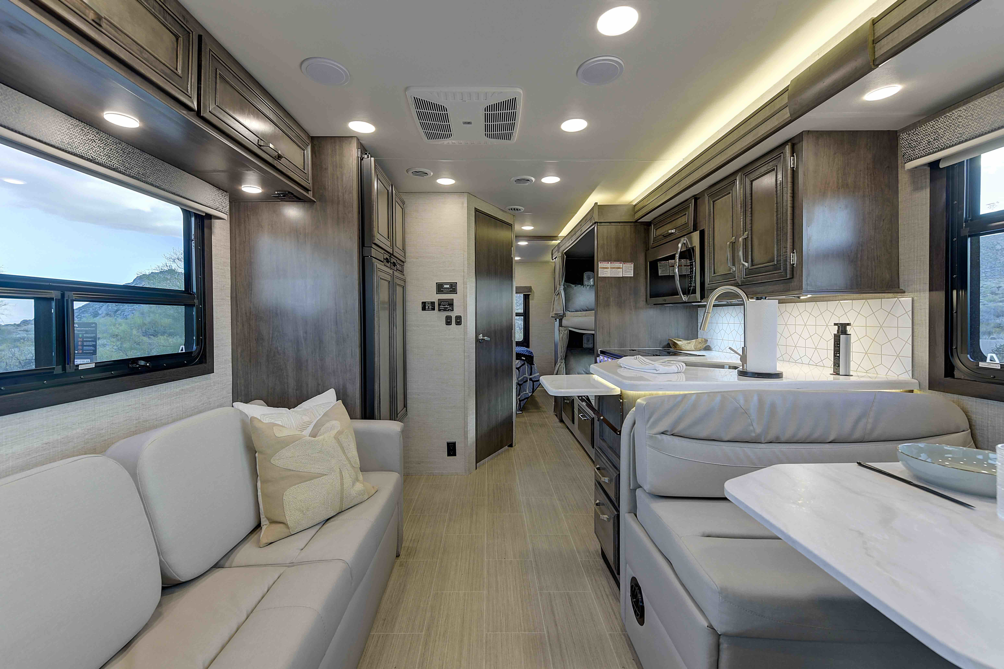 Spacious modern RV rental interior featuring a living area, kitchen, dining booth, and bunk beds, ideal for comfortable travel.. Entegra Coach Esteem 2023
