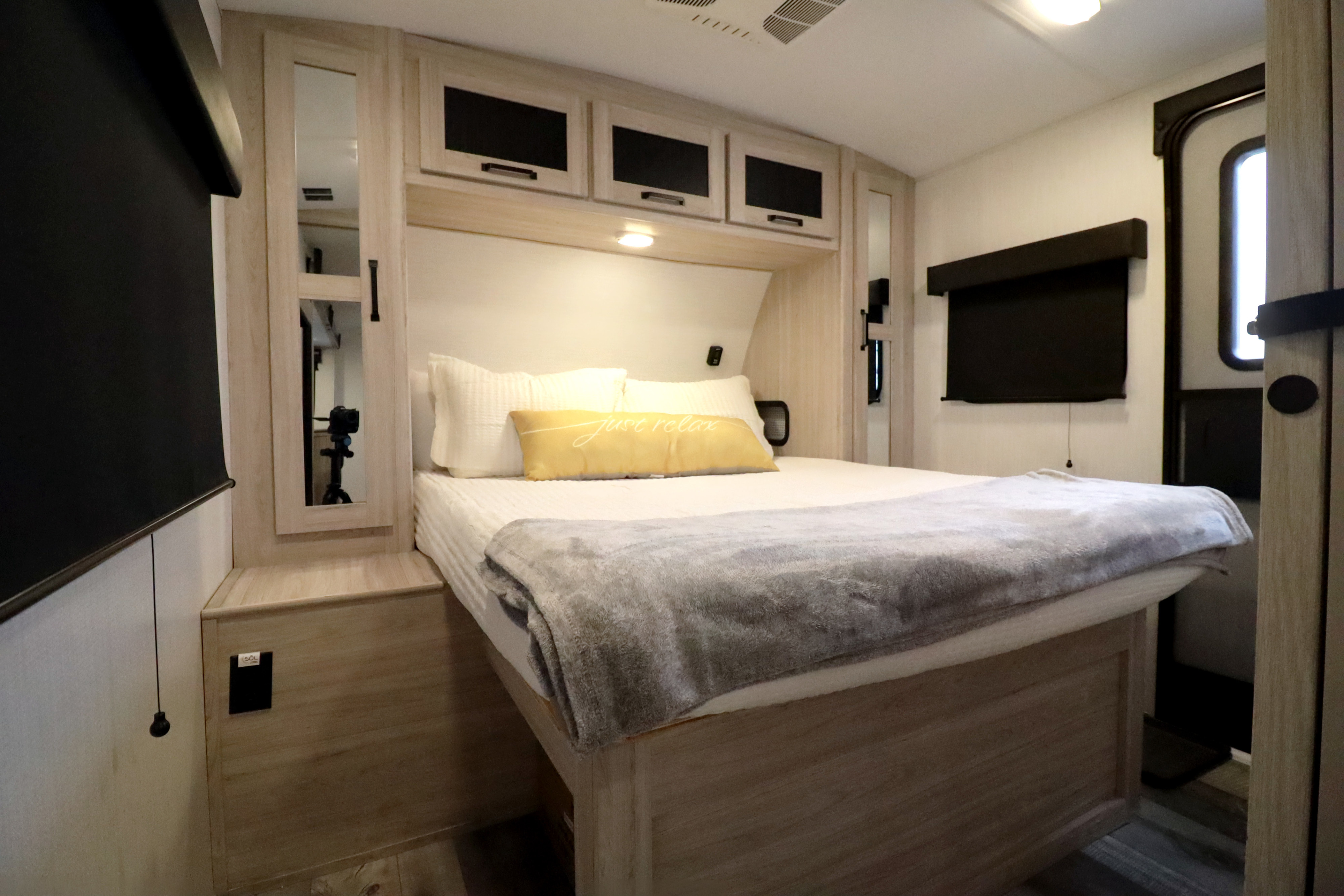 Cozy RV rental bedroom featuring a comfortable bed, ample overhead storage, and pull-down window shades.. Heartland RVs Sundance Ultra Lite 2024