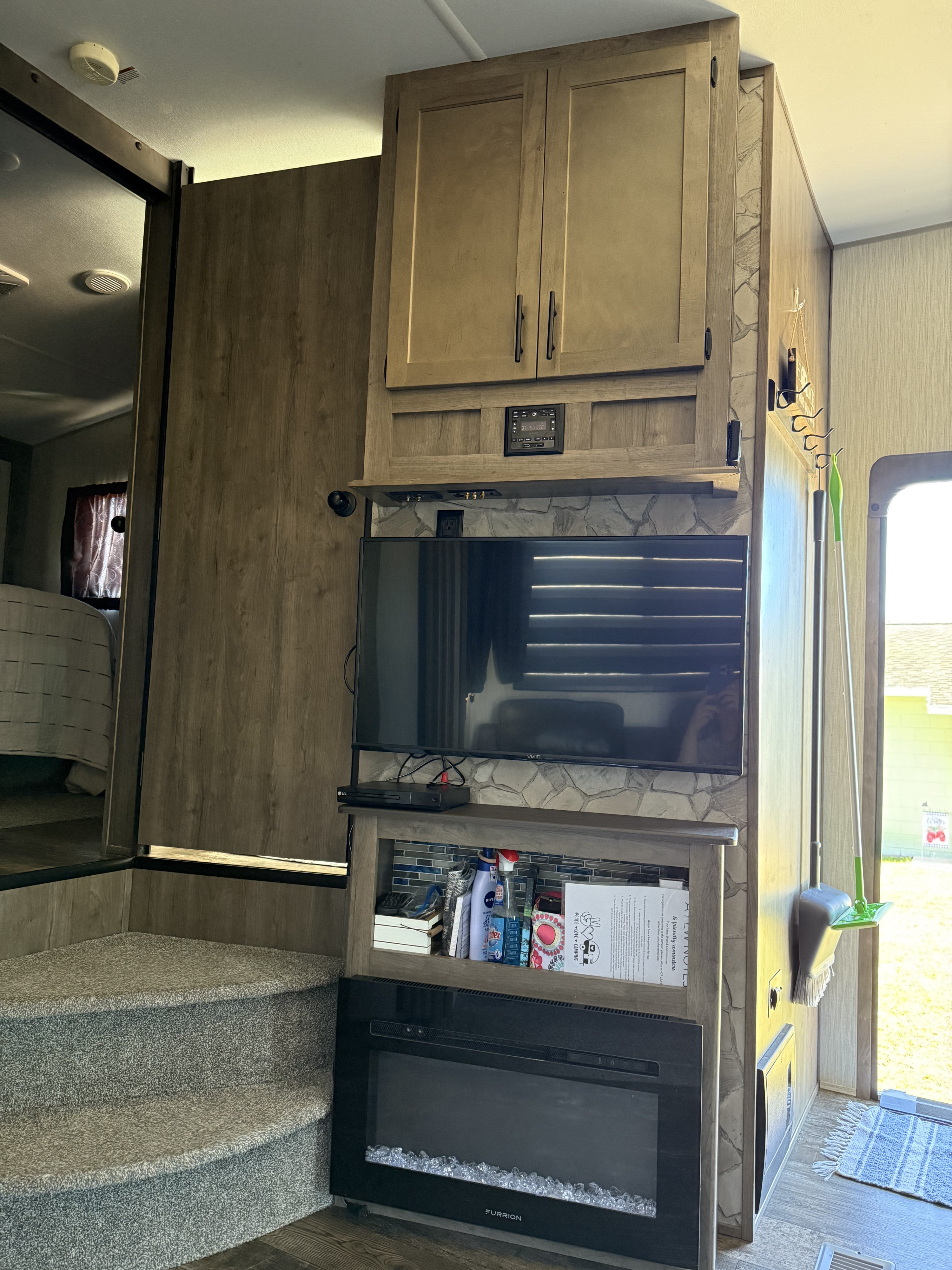 RV rental interior: living area with TV, faux stone, electric fireplace, storage, and carpeted steps to the bedroom.. Forest River Cherokee Wolf Pack Toy Hauler 2021