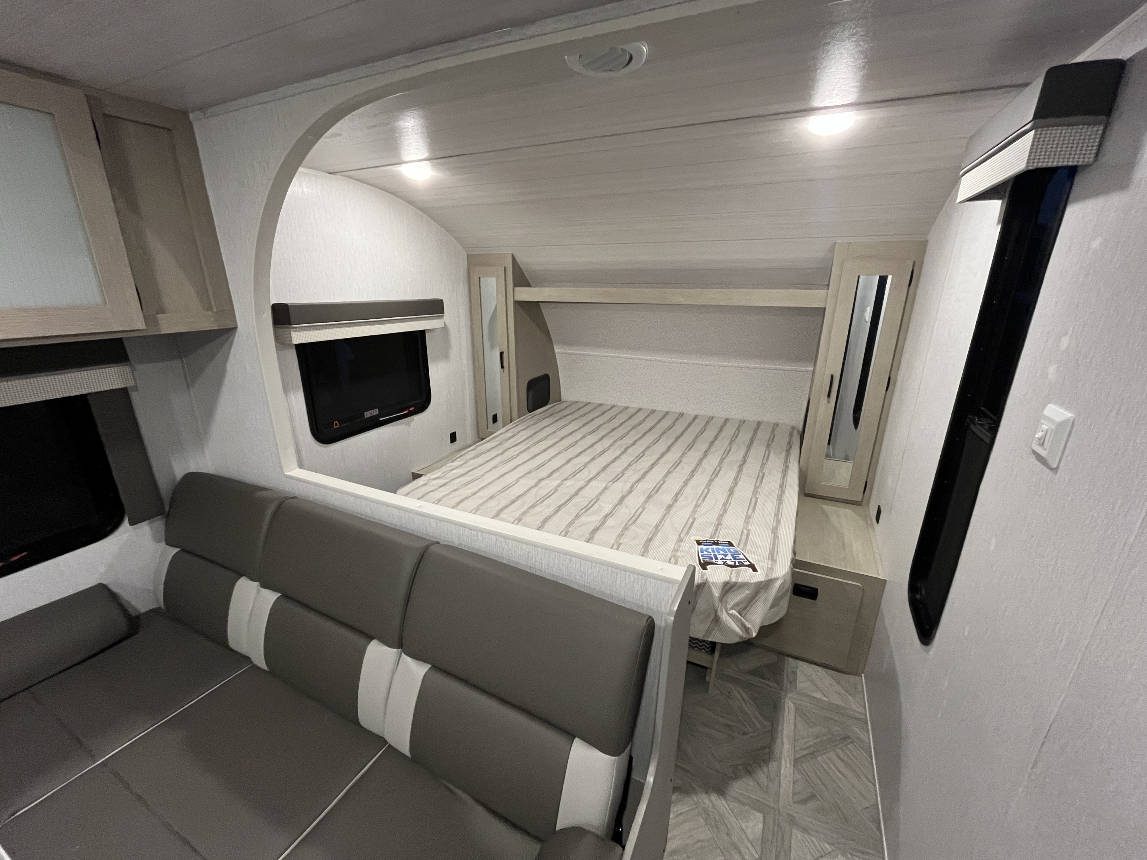 Spacious modern RV rental interior featuring a living area with sofa, and a bedroom with a king-size bed. Bright and inviting.. Forest River Wildwood X-Lite 2023
