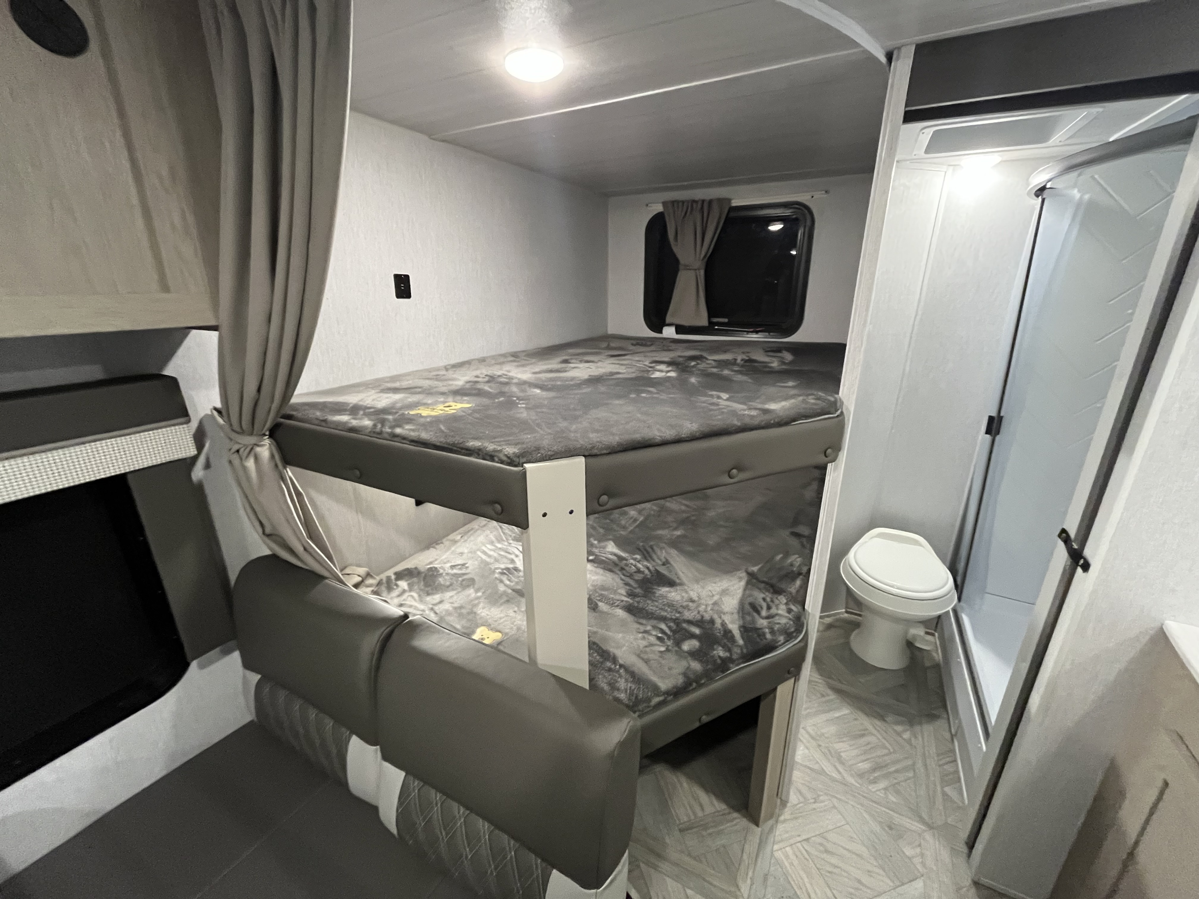 This RV rental features a cozy bunk bed area with a dinette and an adjacent compact bathroom with shower & toilet.. Forest River Wildwood X-Lite 2023
