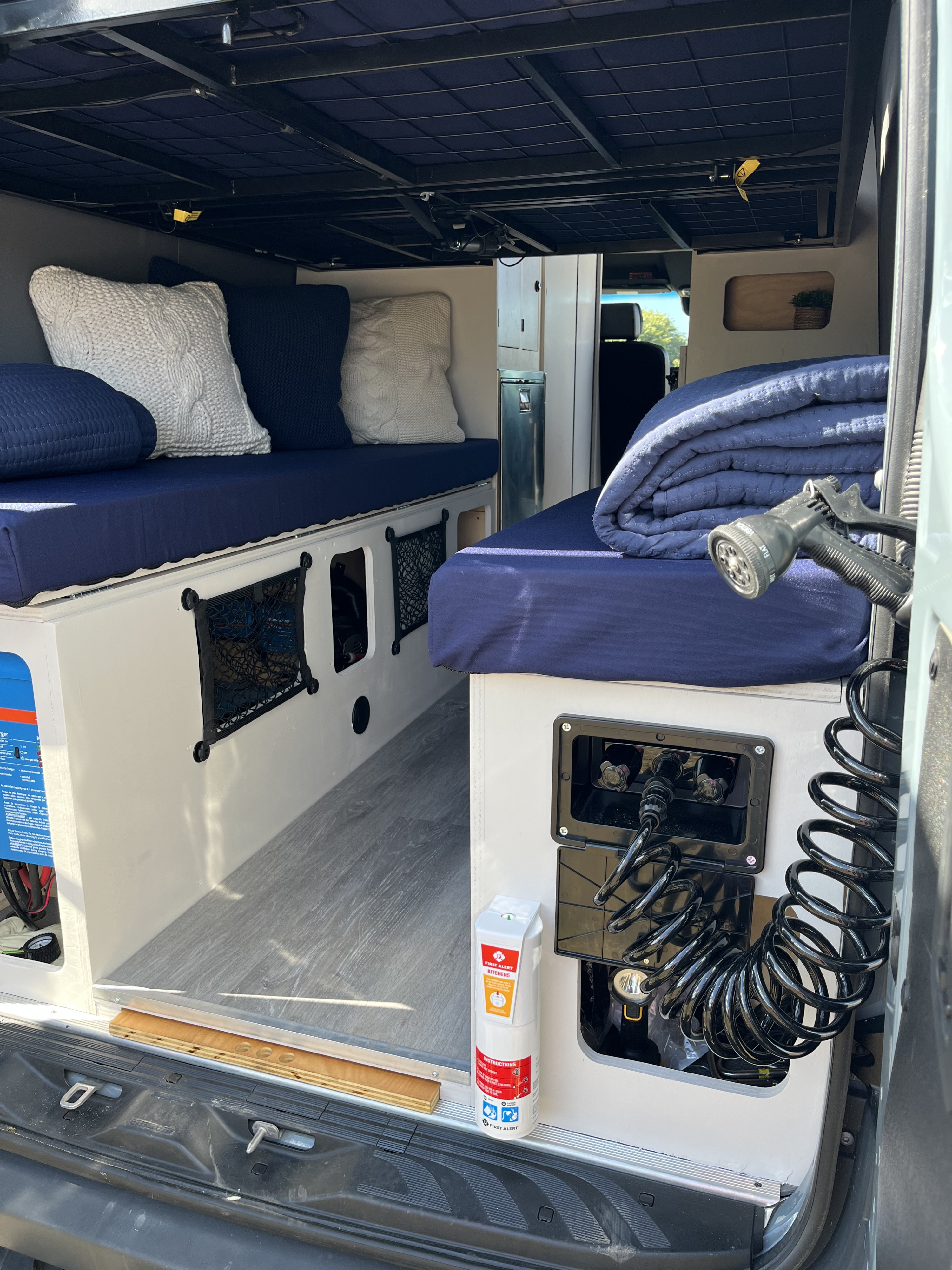 Inside an RV rental: comfortable navy sleeping areas, under-bed storage, and a rear outdoor shower, set up for adventure.. Mercedes benz Sprinter 2022
