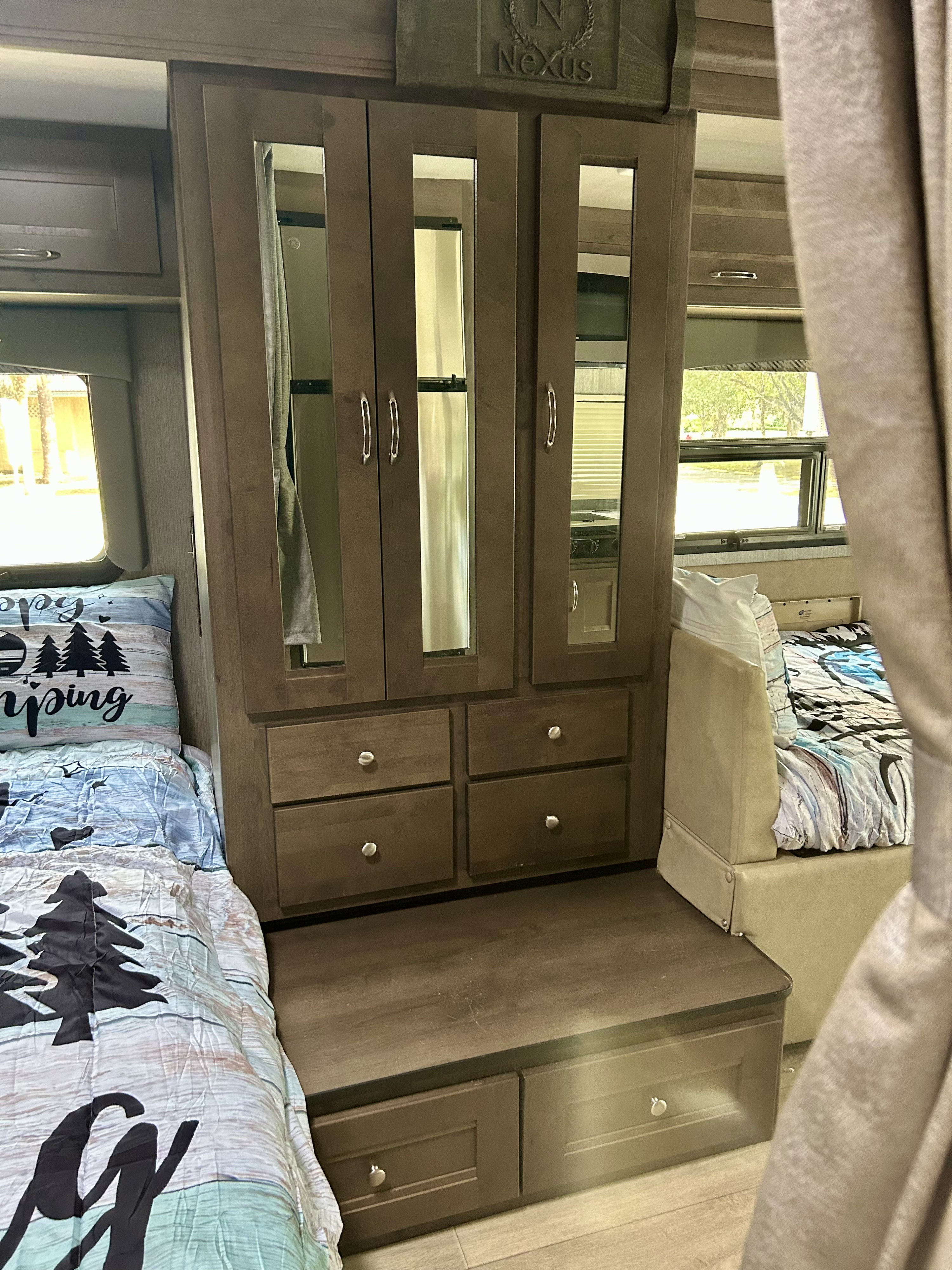 RV rental bedroom features cozy beds with camping decor, ample built-in storage & mirrored wardrobe, plus bright windows.. Nexus RV Phantom 2023