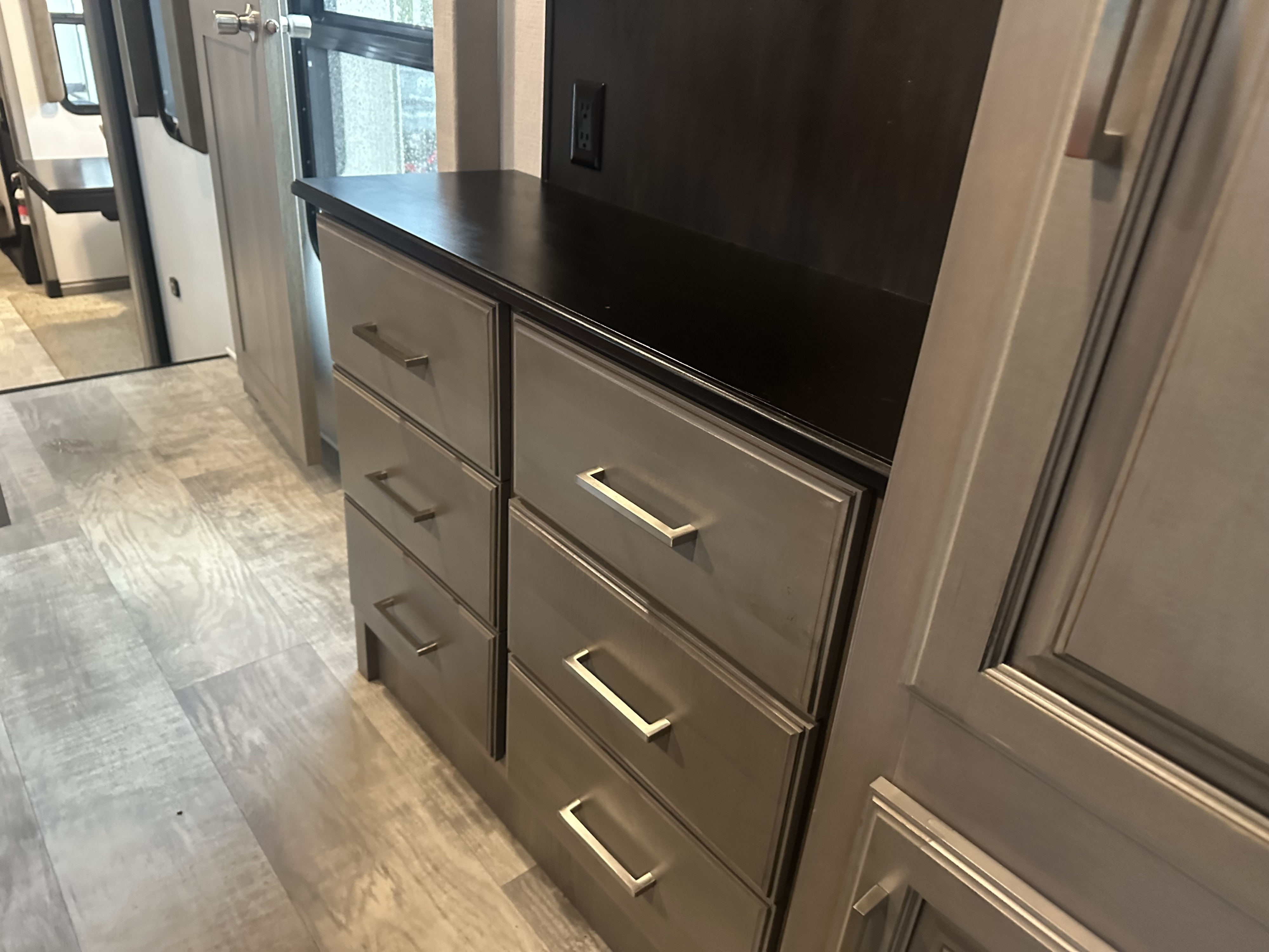Compact RV rental interior: gray storage dresser with dark countertop, power outlet, and laminate flooring.. Keystone RV Montana 2020