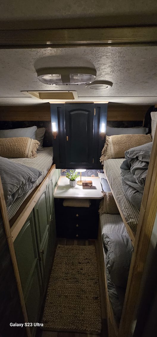 Cozy RV rental interior with comfortable bunk beds on either side, a central rug, and smart storage.. Forest River Rockwood Signature Ultra Lite 2011