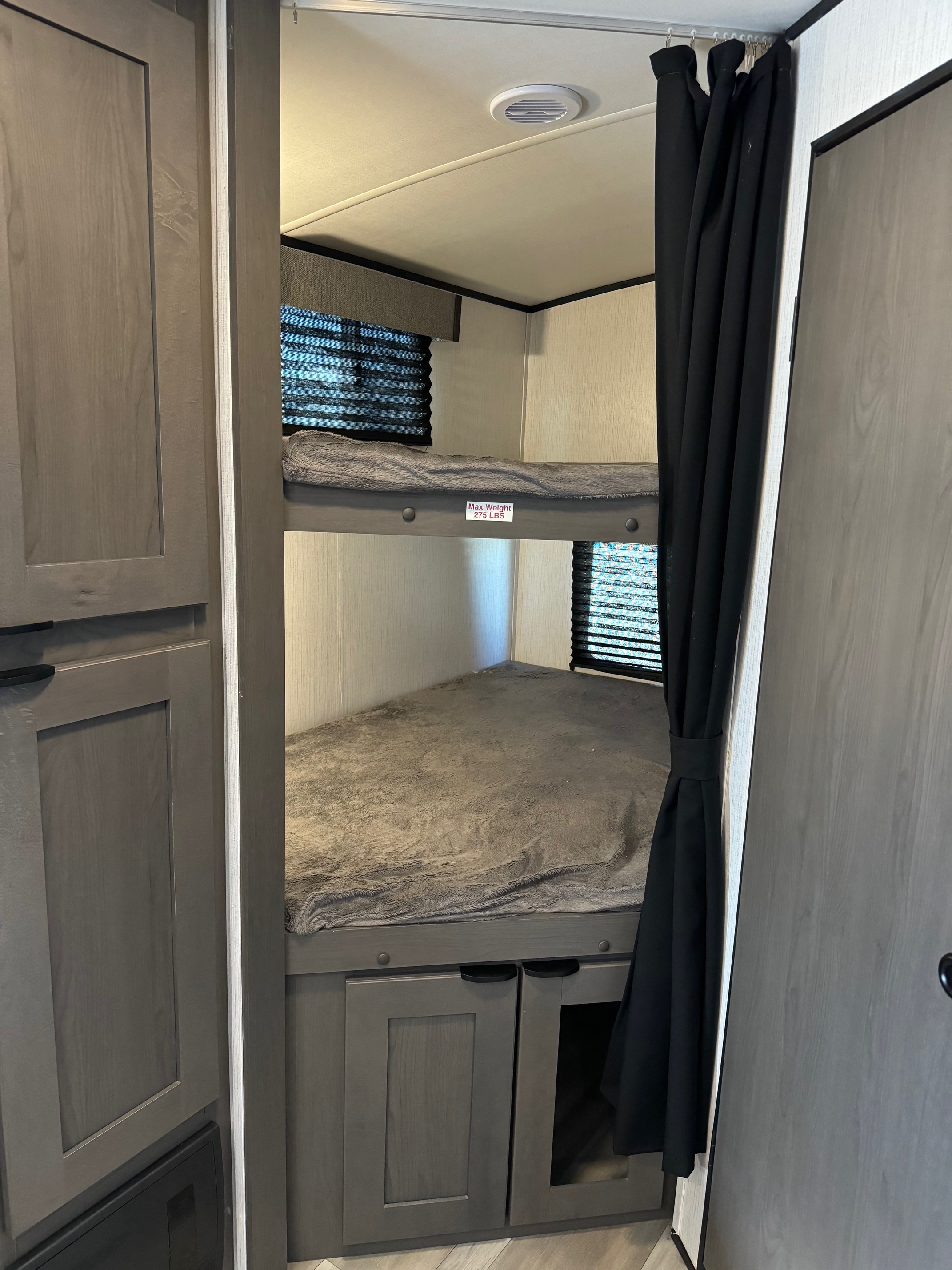 Cozy RV rental interior featuring stacked bunk beds with blankets, window blinds, a ceiling vent, and lower storage cabinets.. Heartland Mpg 2022
