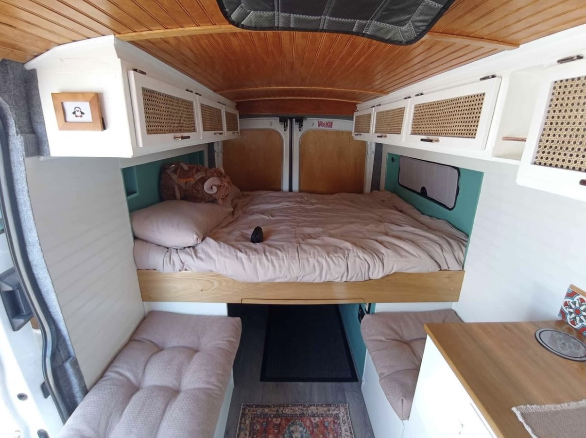 Step inside this cozy RV rental: a compact interior featuring a built-in bed, overhead cabinets, and dual seating benches. Ideal for travel.. Ford Transit 2016