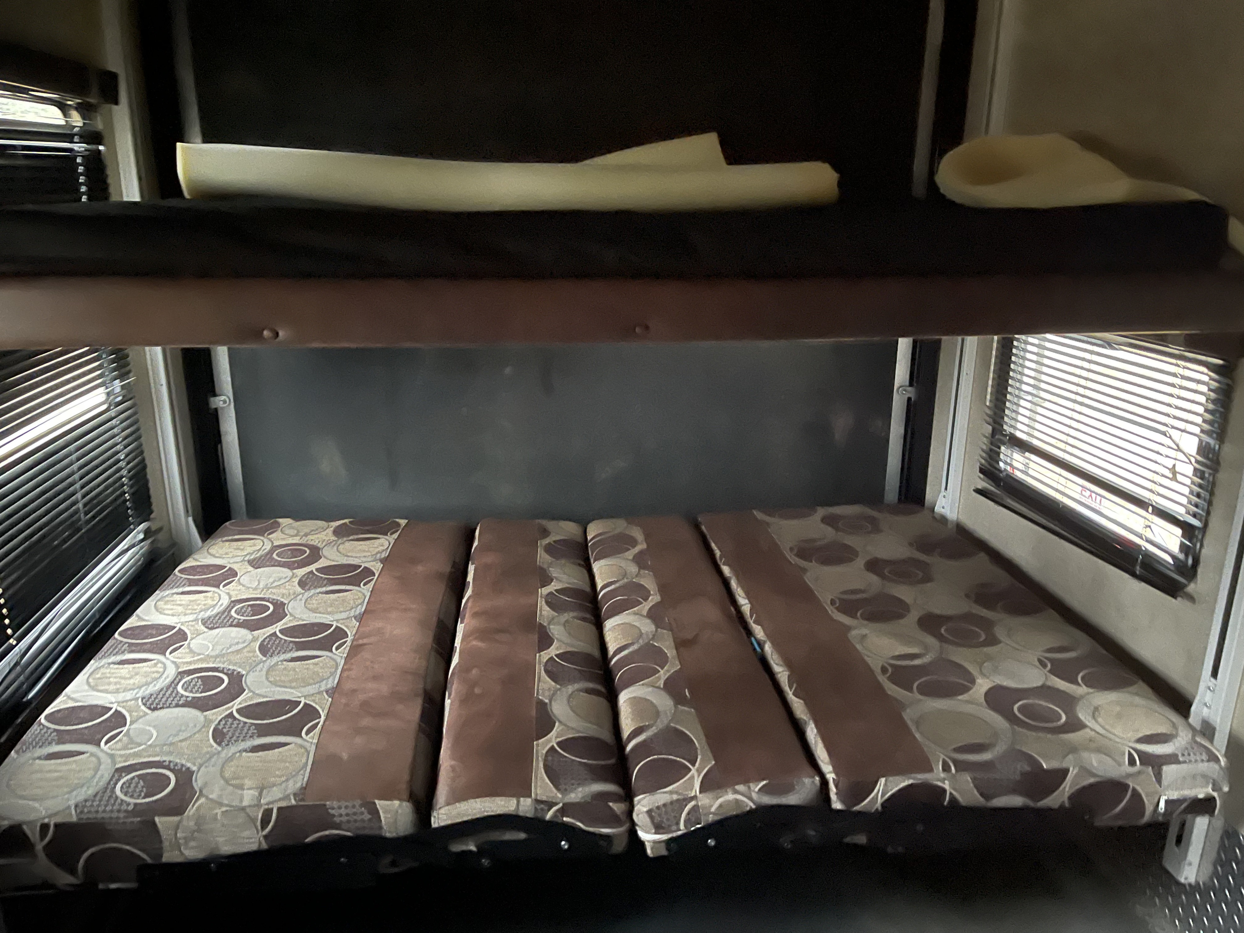 RV rental: Versatile interior with lower convertible bed (patterned cushions) and upper bunk for flexible sleeping.. Keystone Fuzion 2015