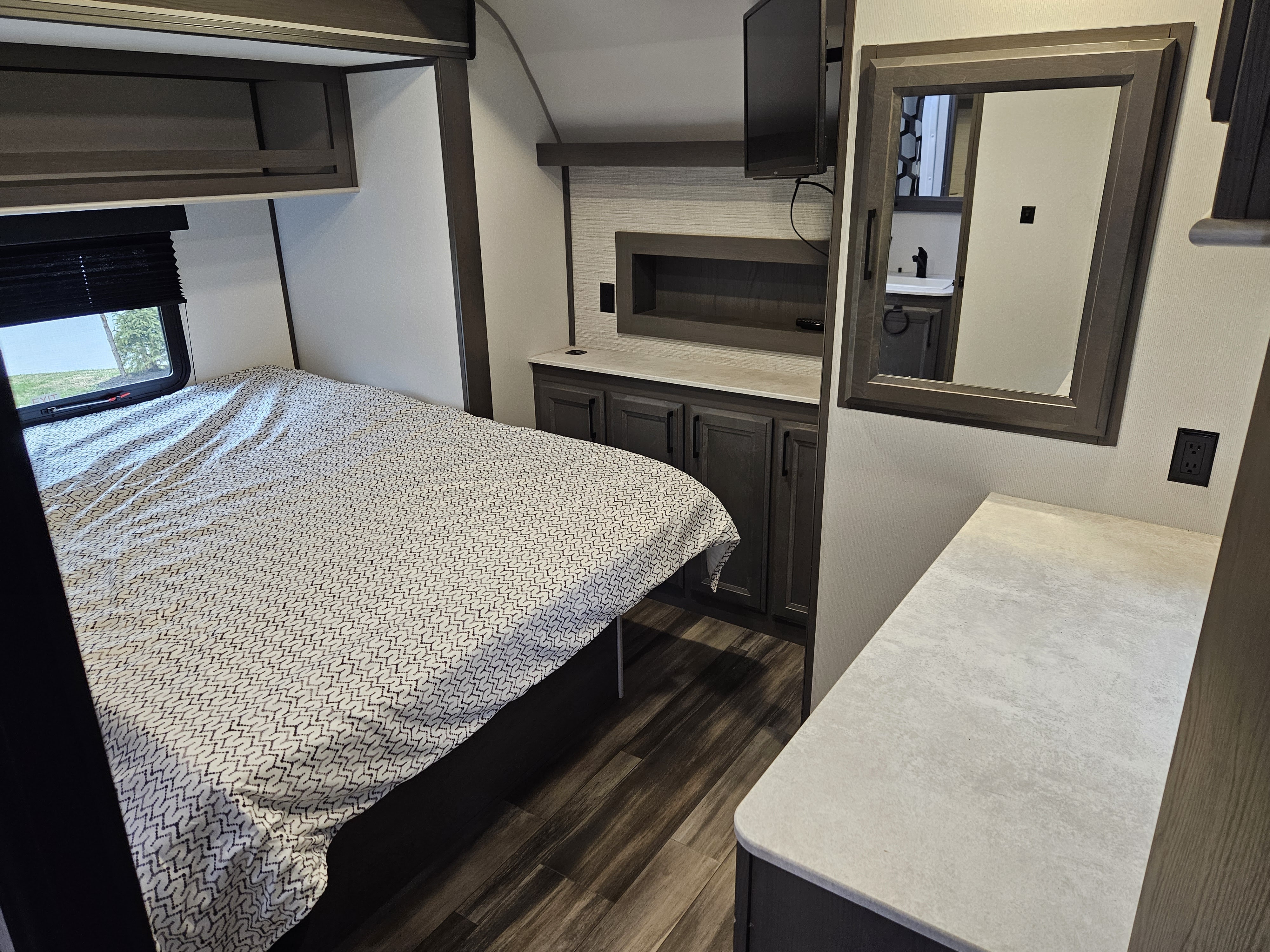 Spacious RV rental bedroom featuring a bed, ample cabinets, wall-mounted TV, and a dresser with a mirror.. Heartland RVs Fuel Toy Hauler 2021
