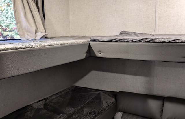 Cozy L-shaped bunk beds in an RV rental, featuring gray upholstery & bedding. This compact sleeping area is functional and neat.. Forest River Salem Cruise Lite 2021