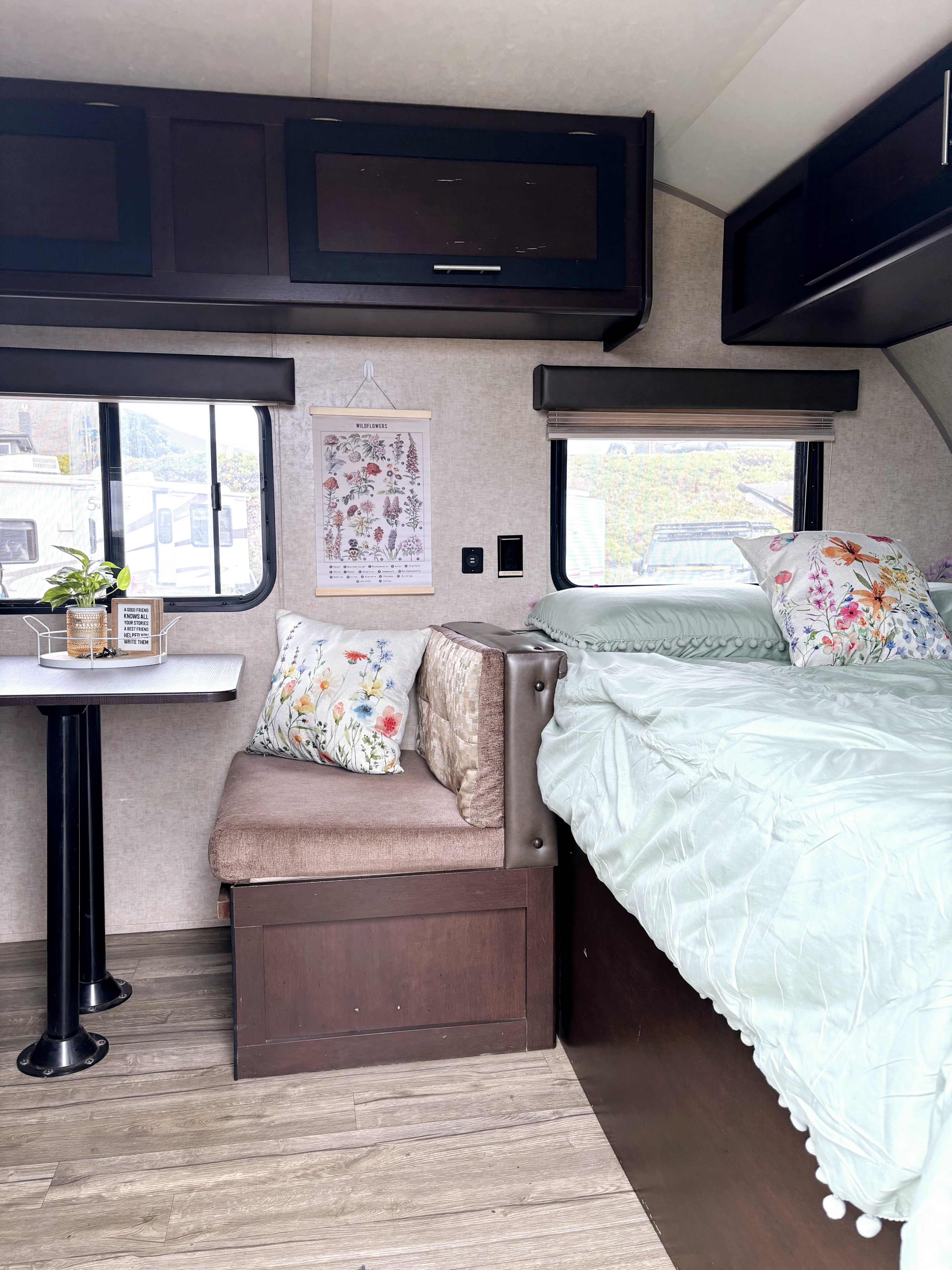 Inside a comfortable RV rental: bed with floral pillows, dinette, and charming decor. Ideal for your next trip.. Forest River Cherokee Wolf Pup Cascade 2017