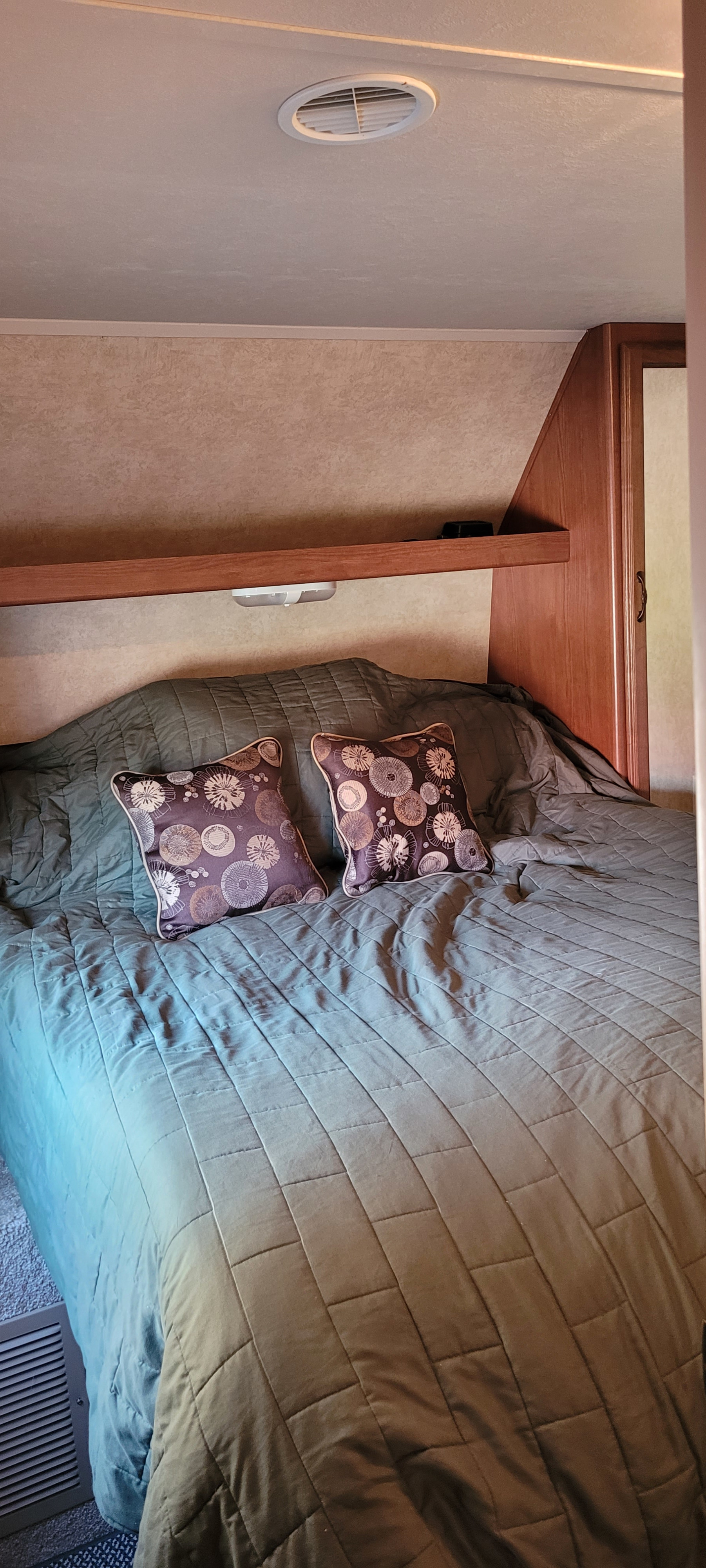 Inside an **RV rental**, this cozy **bedroom** features a quilted bed, two decorative pillows, and overhead storage, perfect for travel.. Forest River Salem 2014